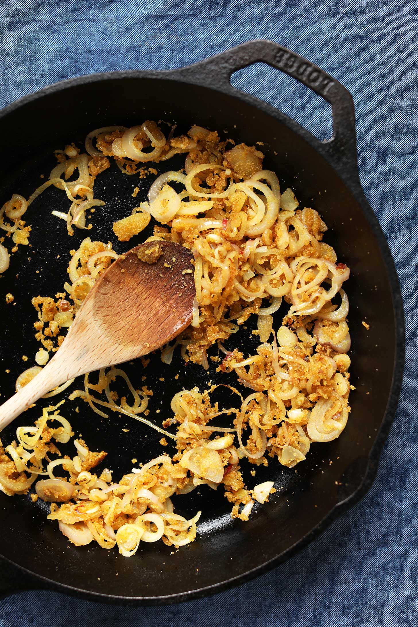 Sautéing onions and spices in a cast iron skillet for healthy gluten-free vegan kale salad