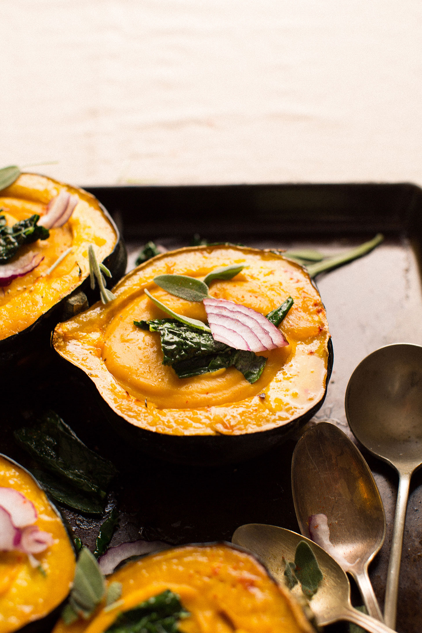 Acorn squash halves filled with squash soup and topped with onions, kale, and sage leaves
