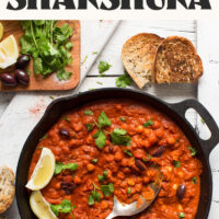 Fresh parsley, lemon, and toasted bread next to a skillet of easy vegan chickpea shakshuka