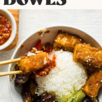 Using chopsticks to pick up a piece of crispy saucy tofu from a bowl