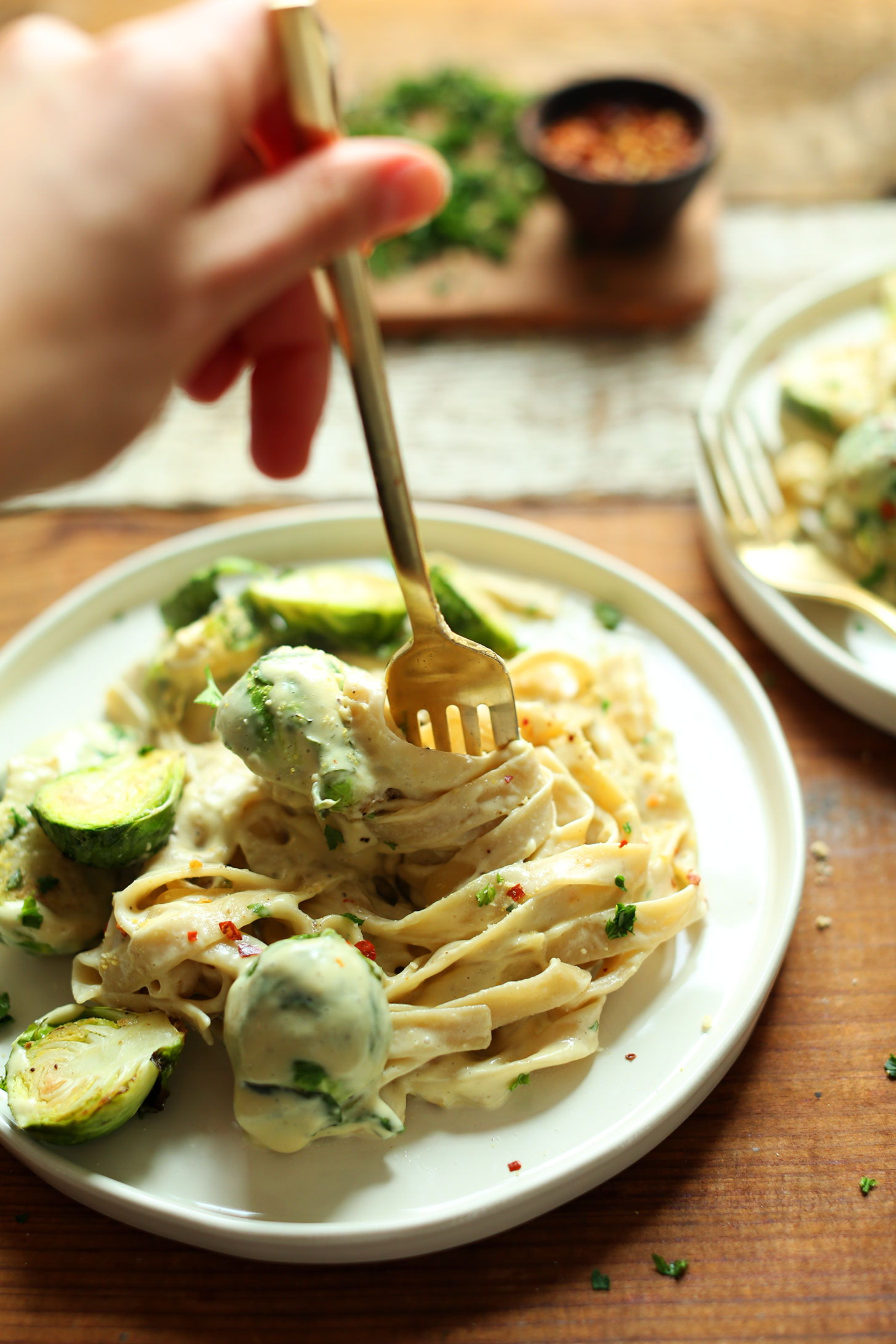 Swirling a fork in a plate of White Wine & Garlic Alfredo Pasta with Brussels Sprouts