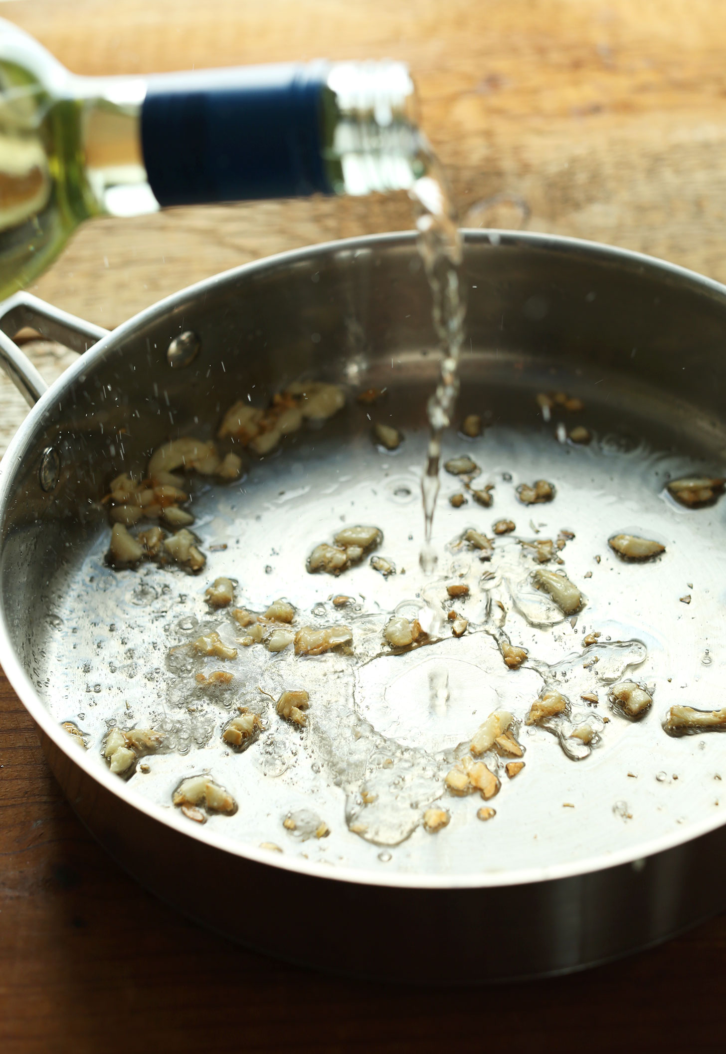 Adding a splash of white wine into a pan for making Gluten-Free Vegan pasta