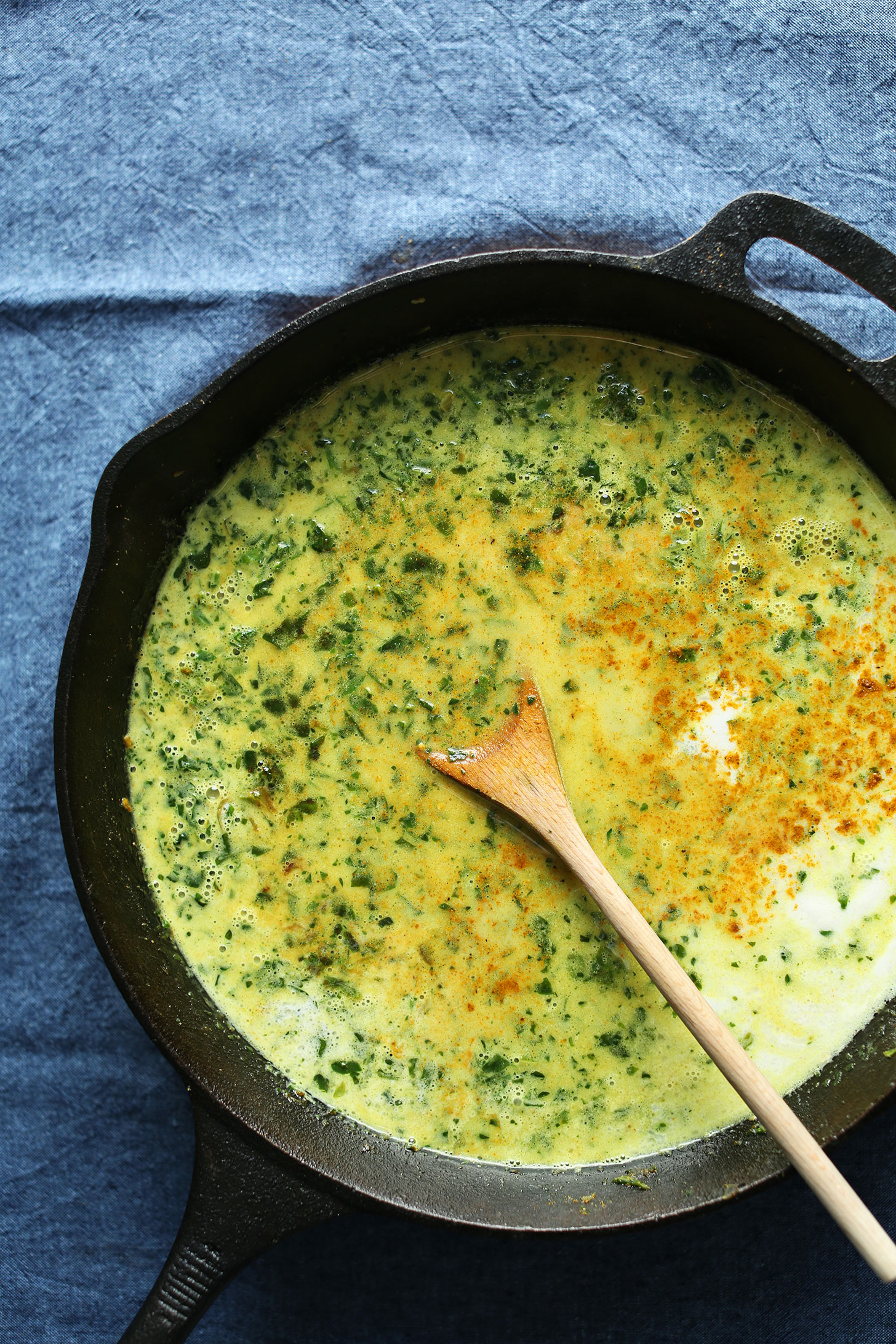 Adding coconut milk and spices to make a delicious vegan green curry for dinner