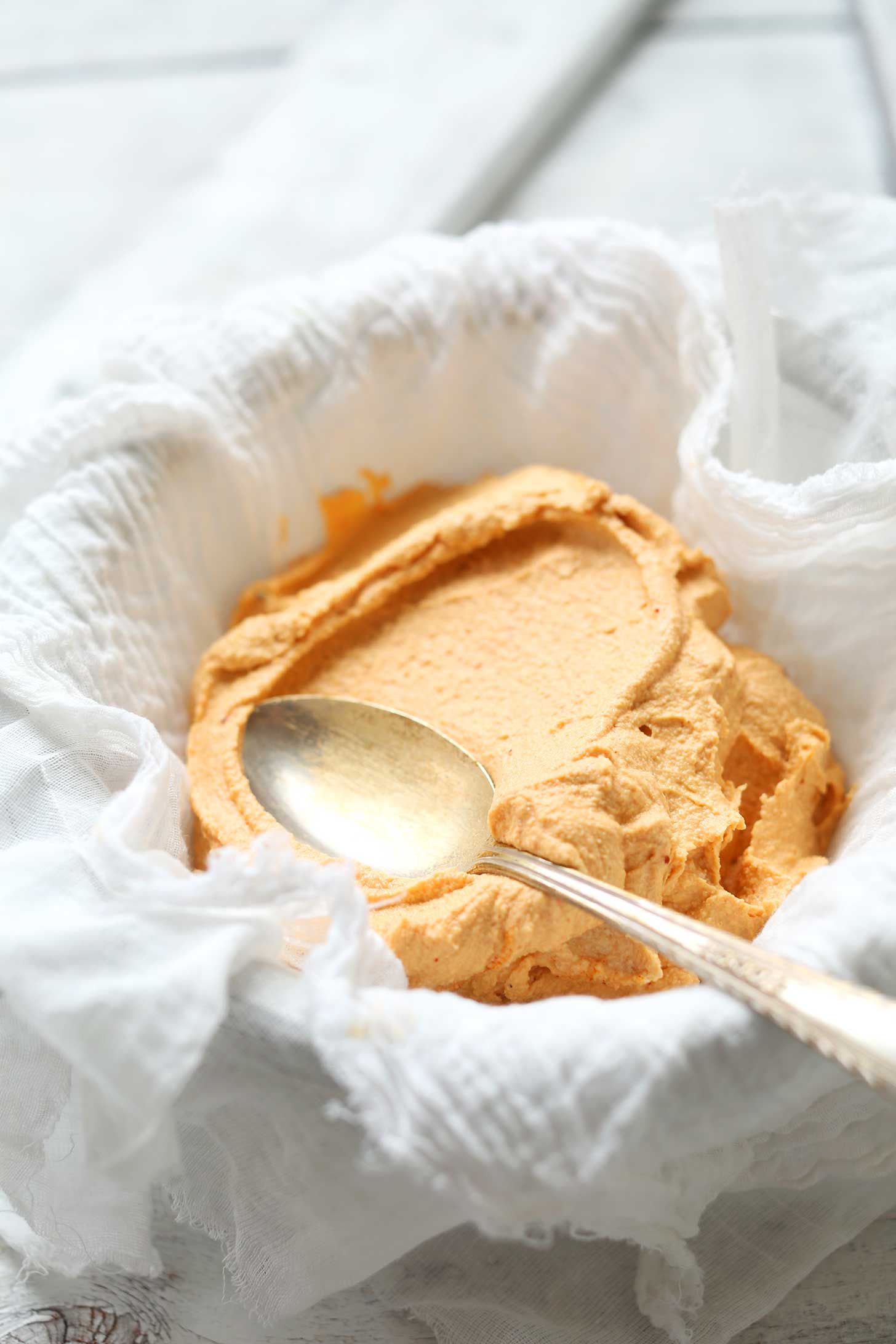 Spreading Spicy Vegan Cheese Ball dough into a cheesecloth for shaping