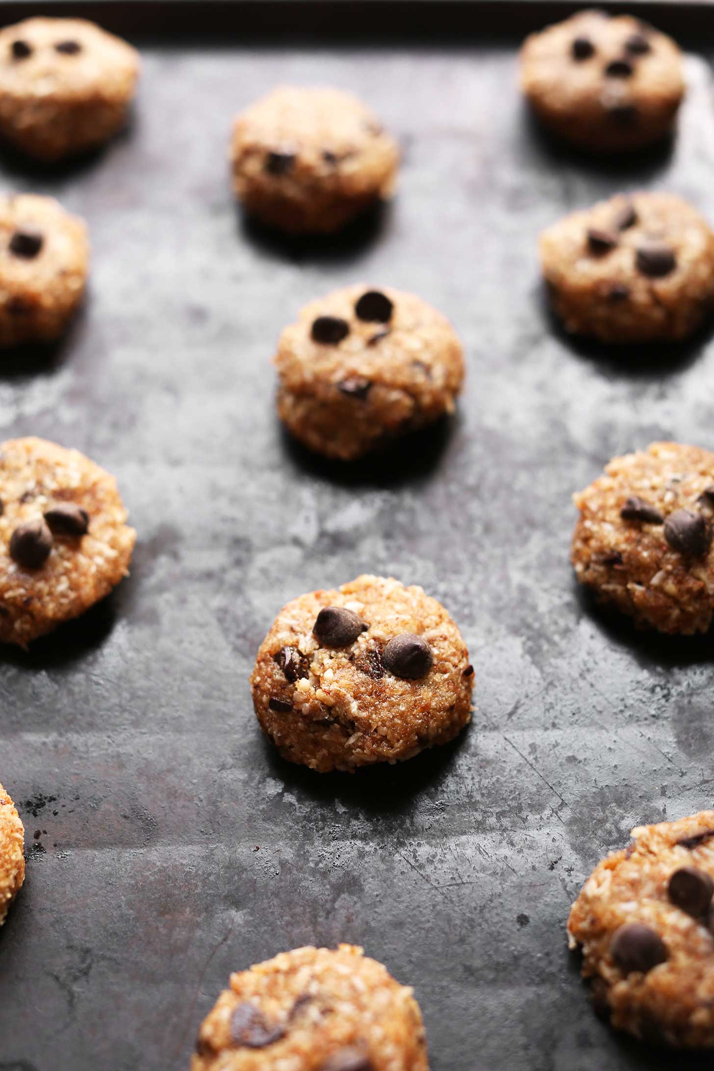 Baking sheet with unbaked vegan almond meal chocolate chip cookies