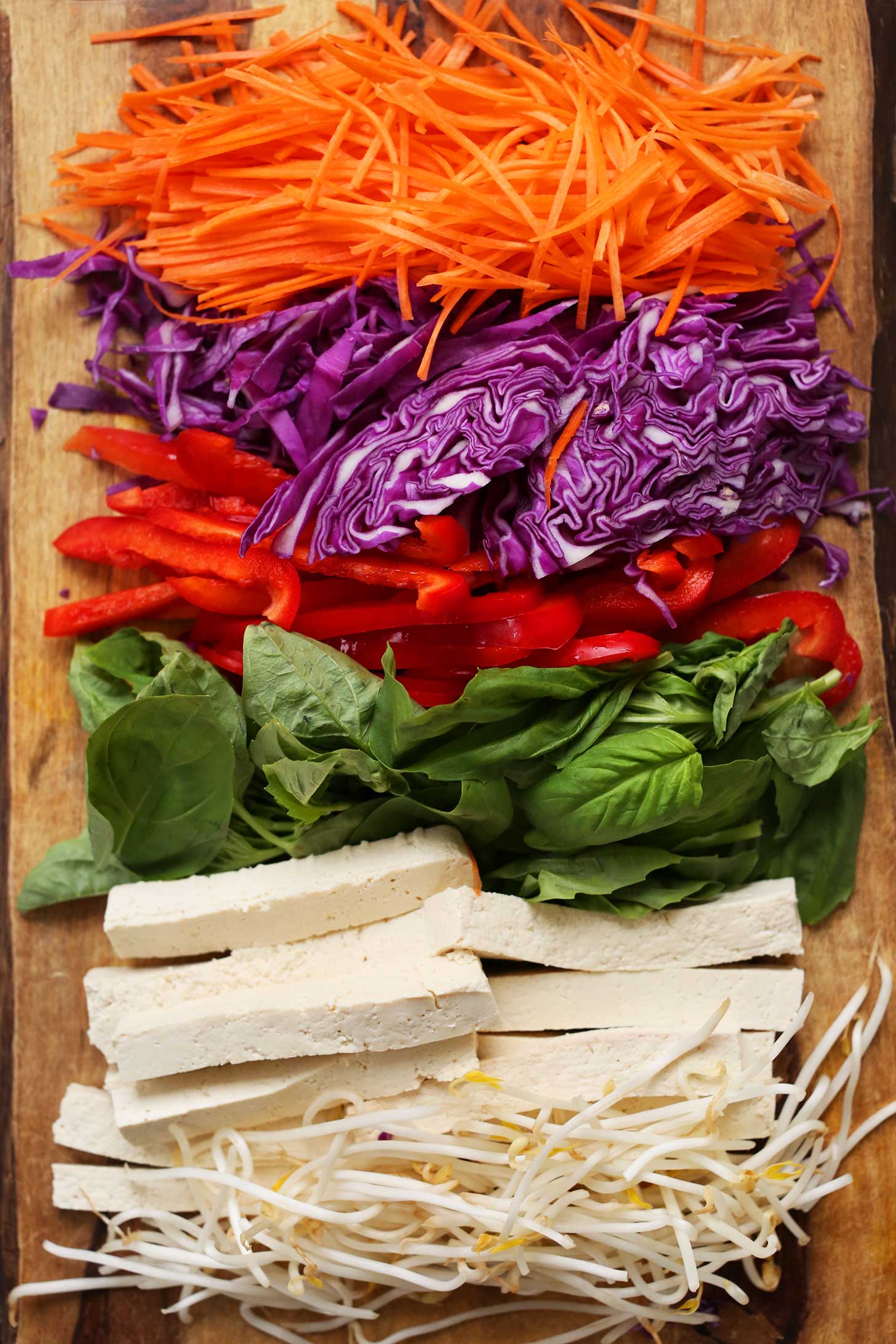 Shredded carrots, cabbage, bell pepper, basil, tofu, and bean sprouts for making homemade vegan salad rolls