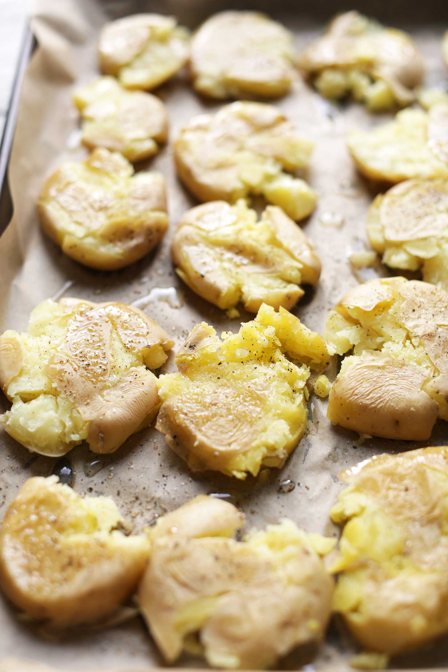 Parchment-lined baking sheet with vegan smashed potatoes