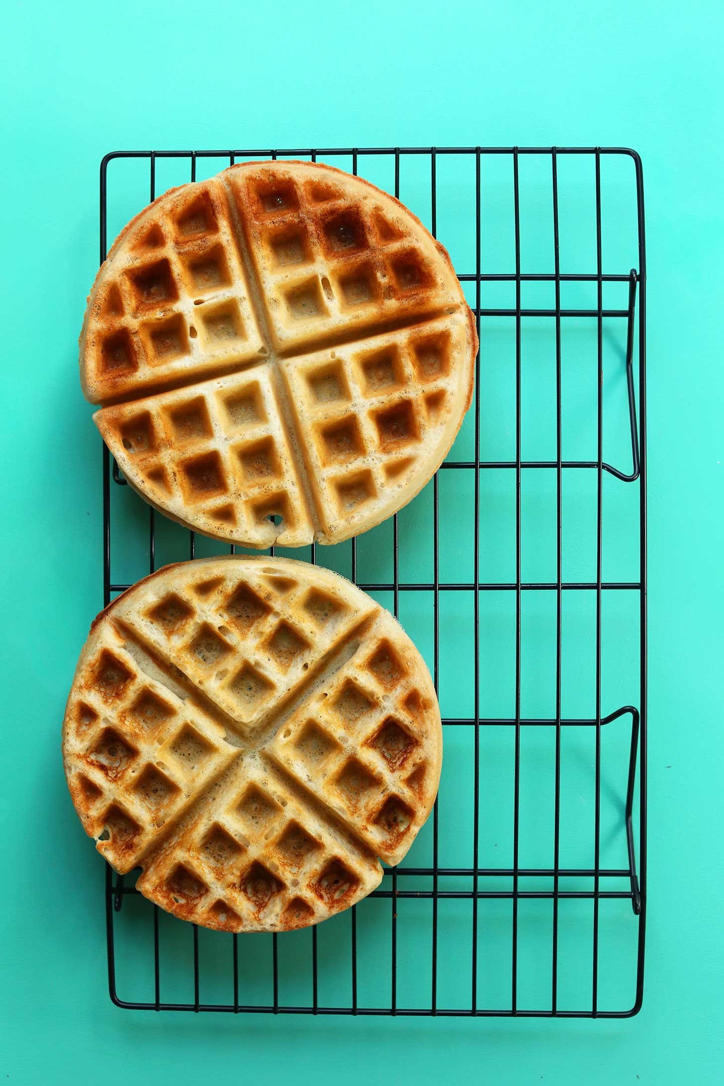 Two perfectly browned Vegan Gluten-Free Waffles on a cooling rack