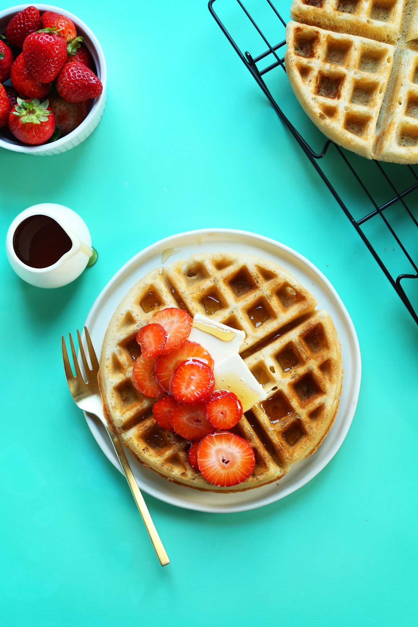 Plate with the perfect Vegan Gluten-Free Waffle topped with syrup, vegan butter, and fresh strawberries
