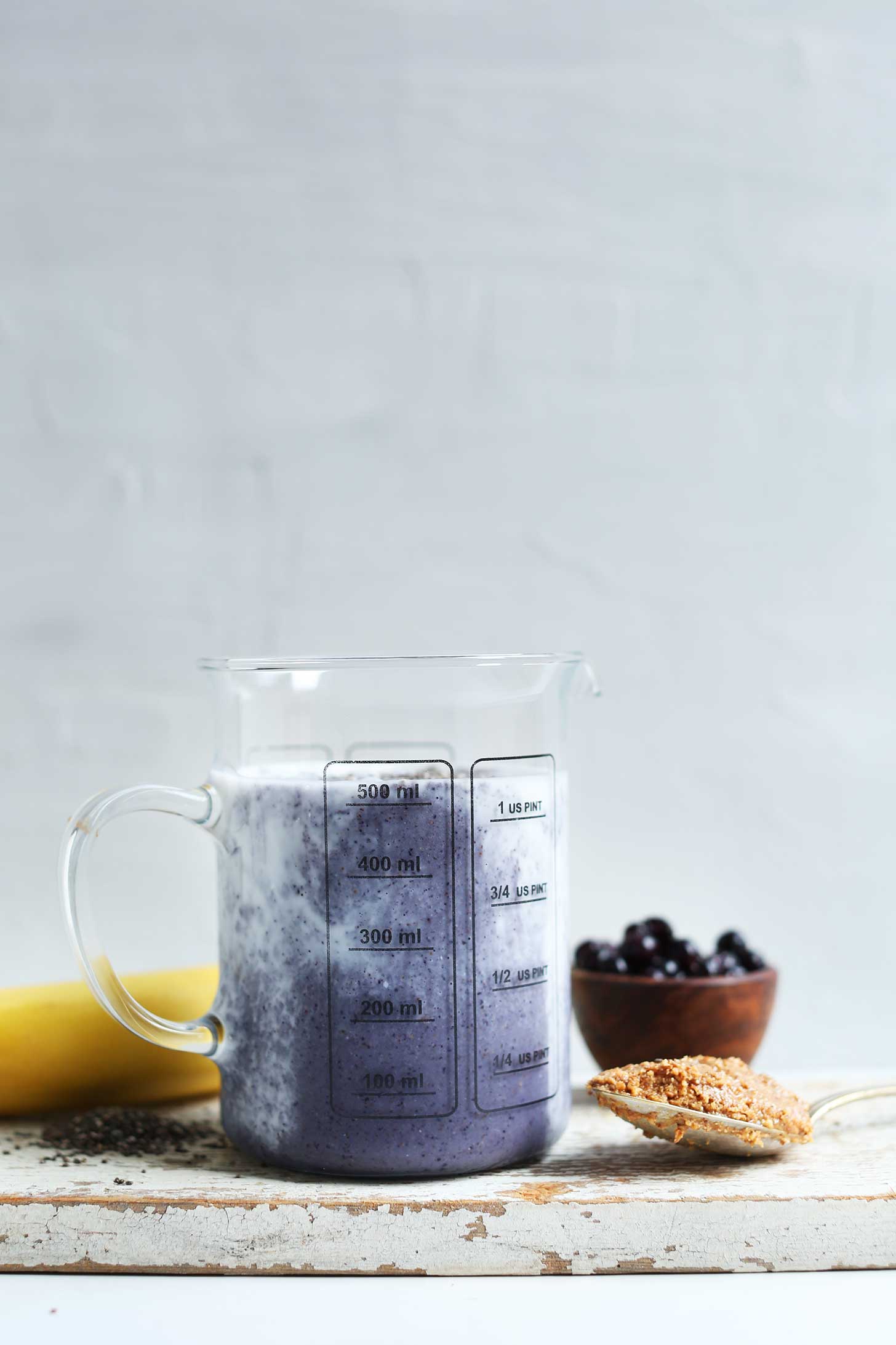 Glass measuring jar filled with creamy vegan Almond Butter Blueberry Smoothie