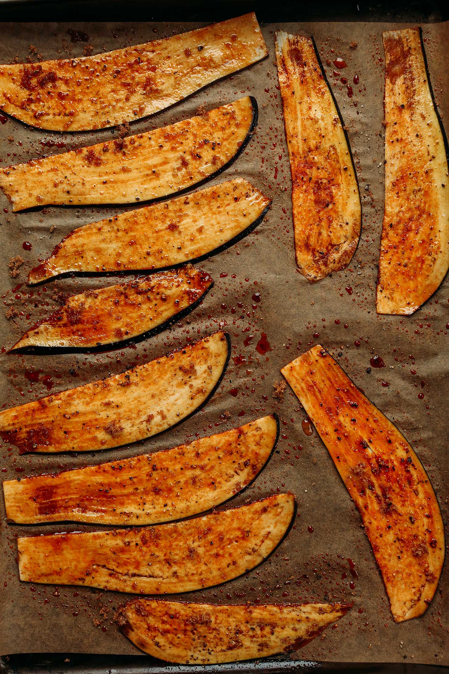 Smoky vegan Eggplant Bacon slices on a parchment-lined baking sheet