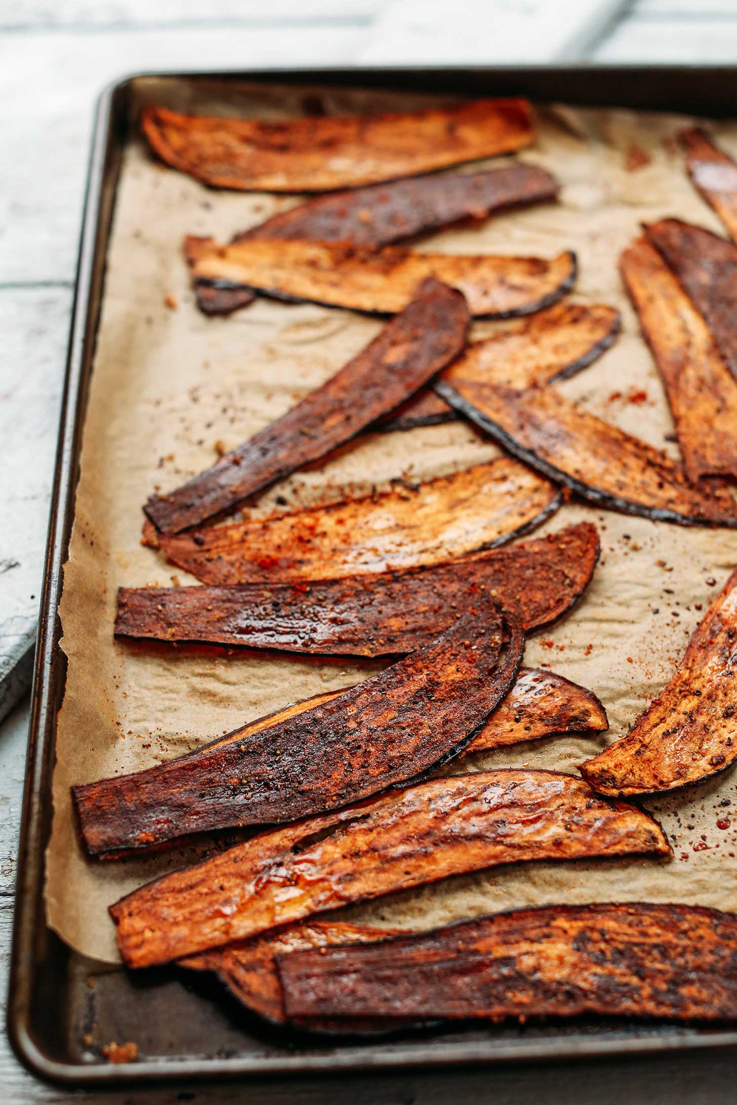 Parchment-lined baking sheet with Crispy Eggplant Bacon slices