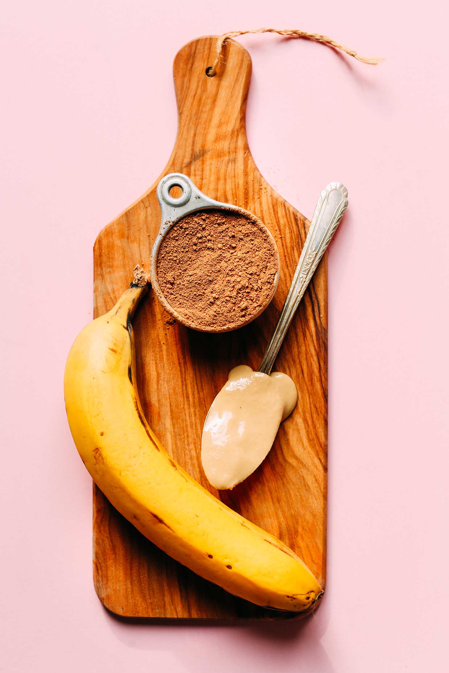 Cocoa powder, tahini, and banana on a wood board for making healthy Chocolate Tahini Banana Ice Cream