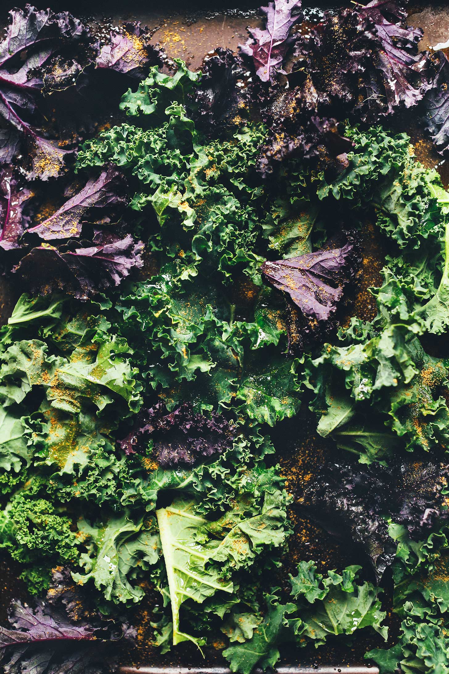 Parchment-lined baking sheet filled with kale for making into crunchy kale chips for nachos