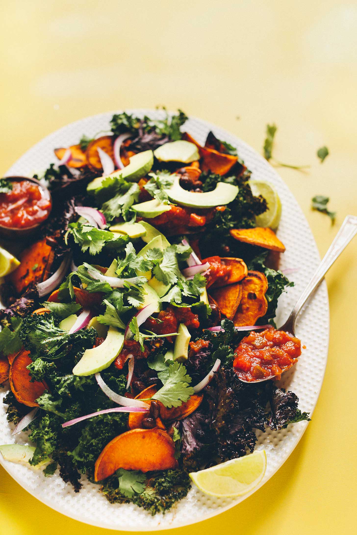 Big plate of plant-based Kale Nachos with Black Beans, Sweet Potatoes, Avocado, and salsa