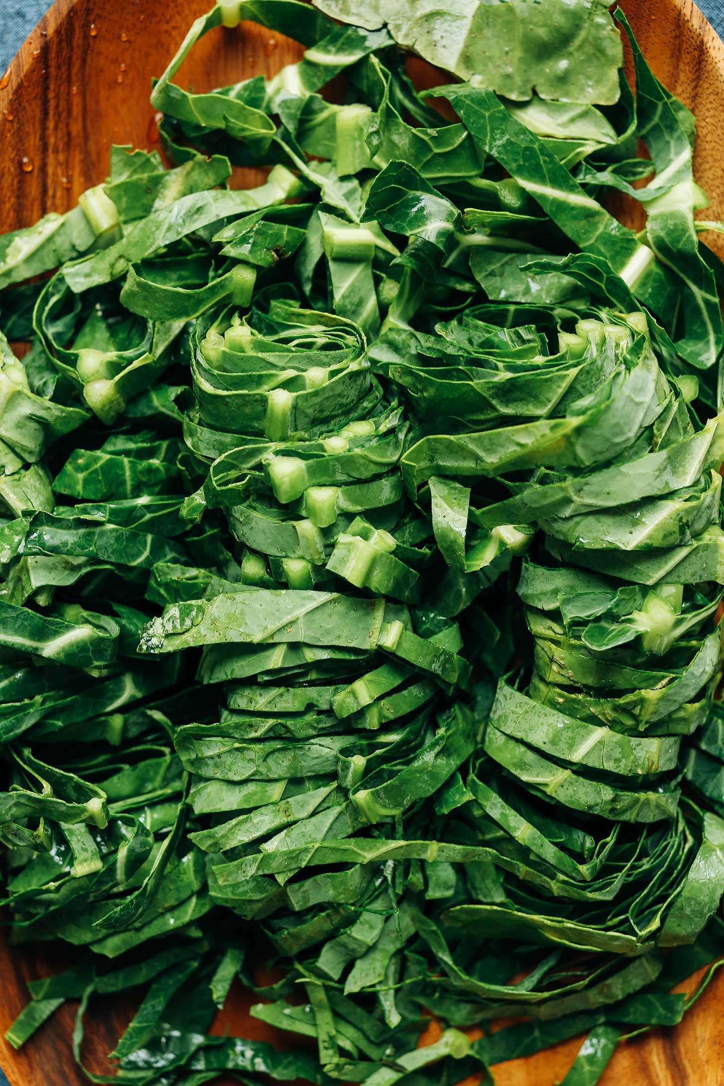 Chopped collard greens on a wood platter for making vegan Collard Greens with Coconut Bacon