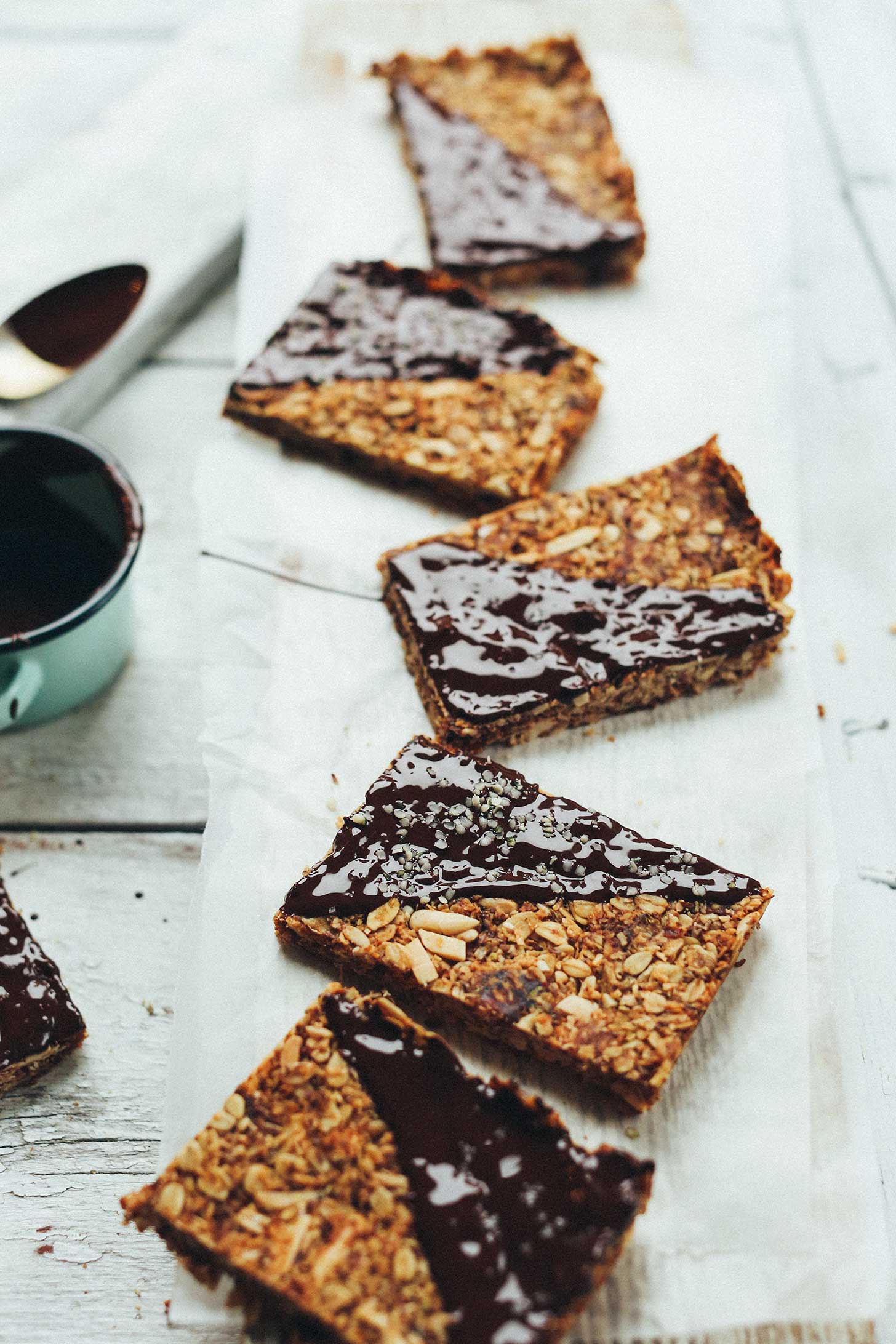 Cut gluten-free chocolate-dipped granola bars arranged on a wood plank