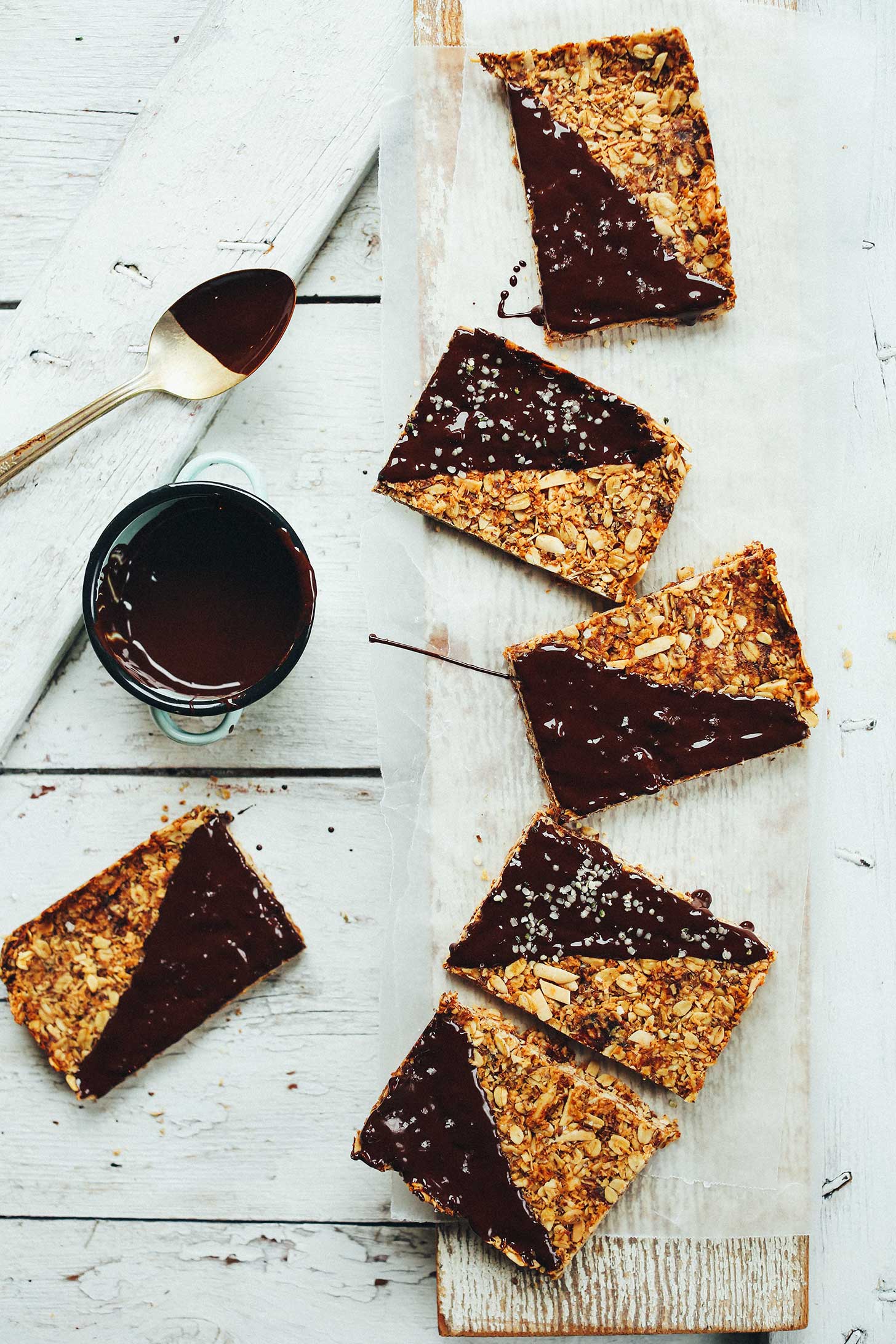 Chocolate dipped gluten-free Crunchy Baked Granola Bars on a wood plank