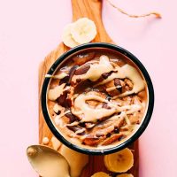 Banana slices around a bowl of Vegan Tahini Chocolate Soft Serve
