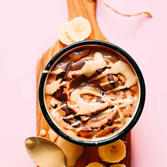 Banana slices around a bowl of Vegan Tahini Chocolate Soft Serve
