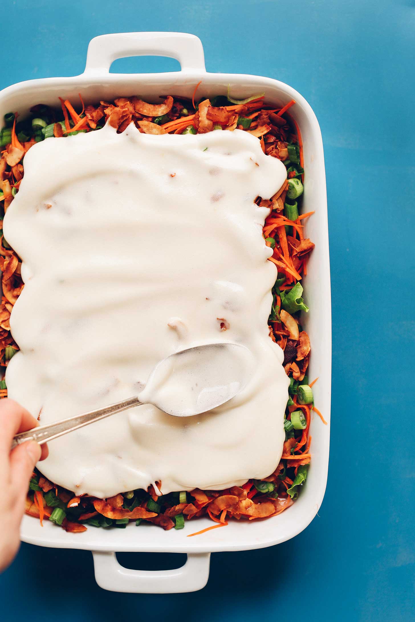 Spreading aquafaba mayo over our Vegan 7-Layer Salad