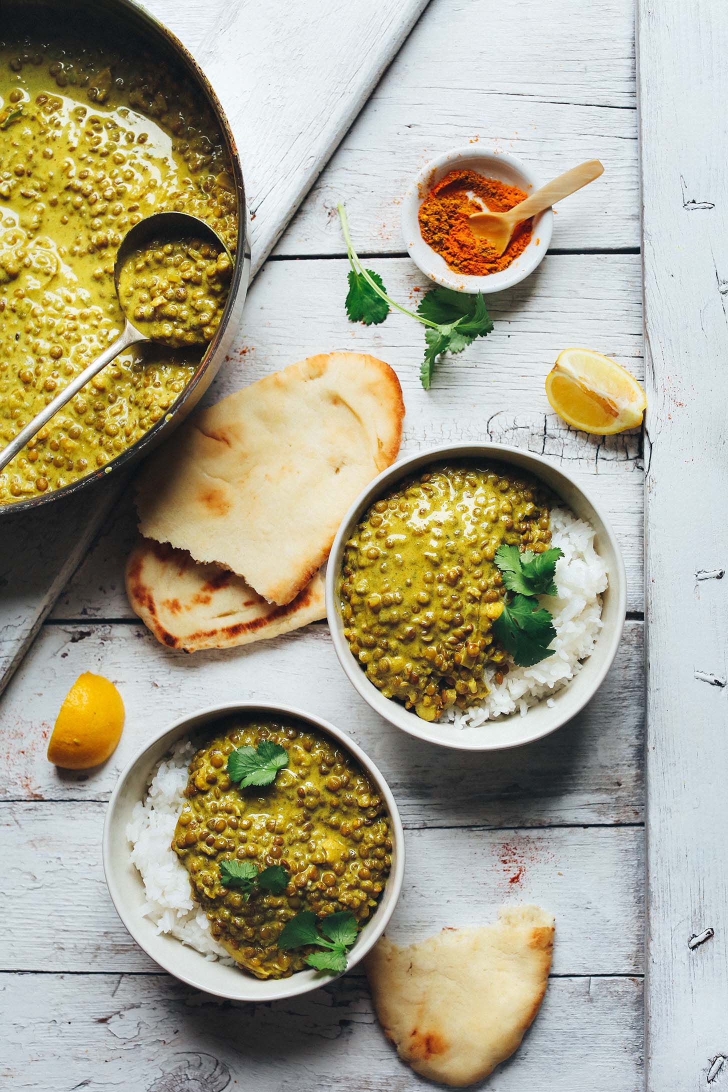 Bowls and pan filled with 1-Pot Vegan Lentil Dal made with green curry paste
