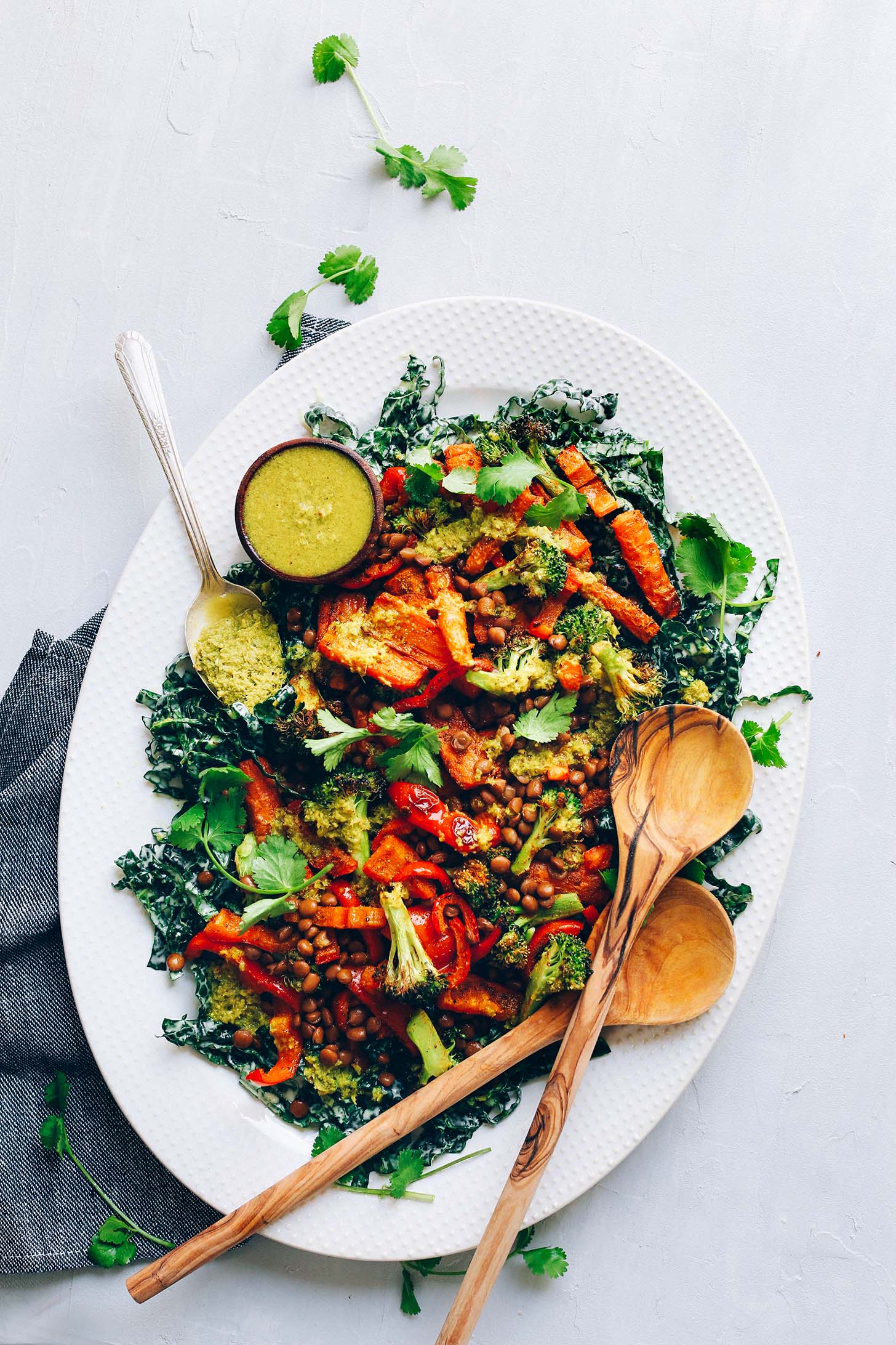Ceramic platter with Kale, Roasted Veggies, Lentils and Green Curry dressing for a delicious plant-based meal