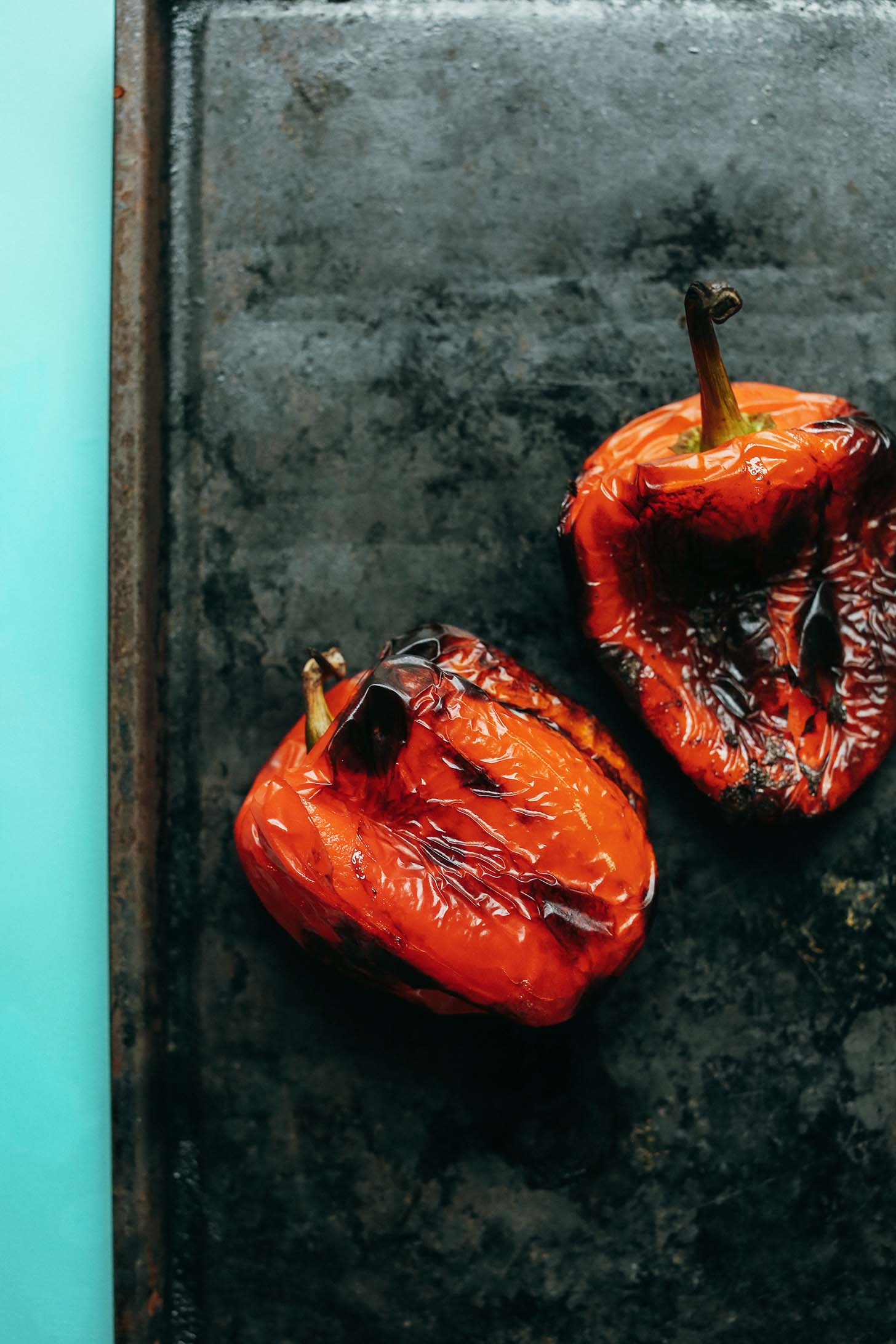 Roasting two red bell peppers on a baking sheet for Creamy Vegan Roasted Red Pepper Tomato Soup