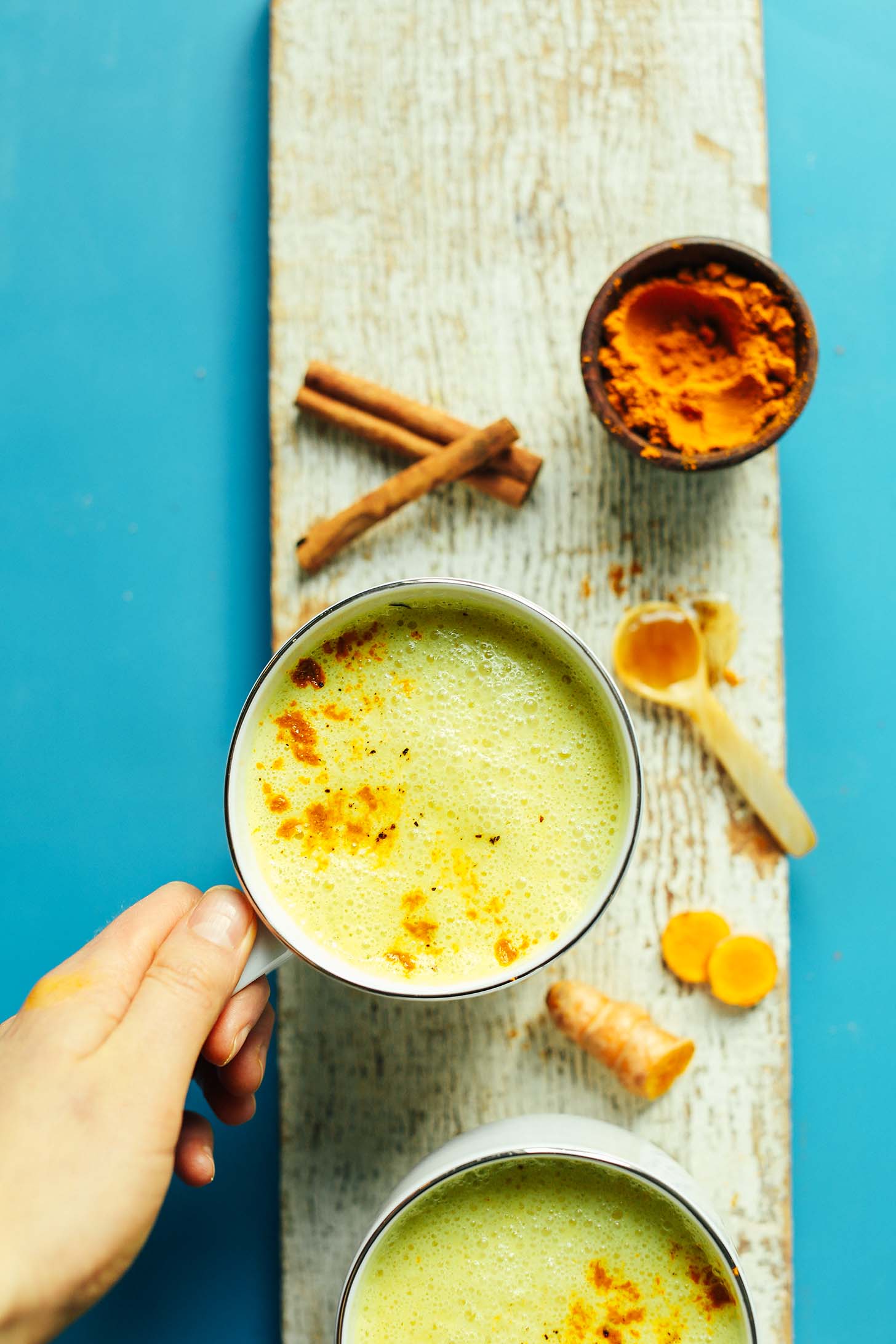 Wood platter with a mug of vegan Golden Milk and spices