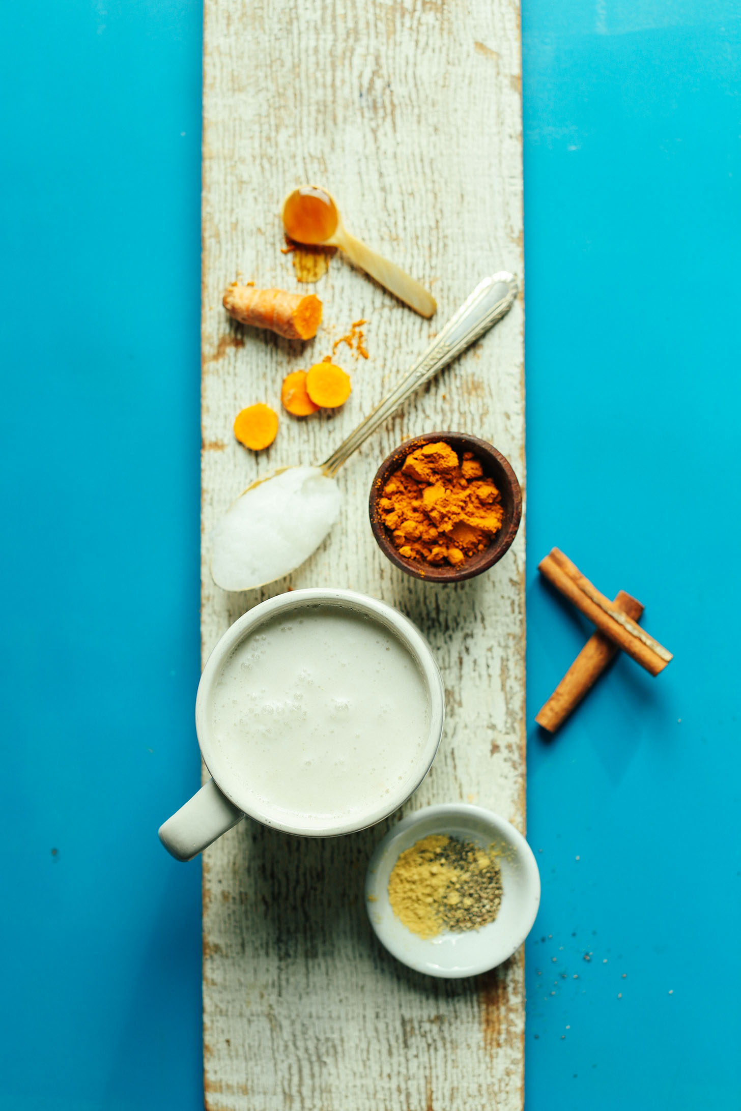 Wood plank with coconut milk, coconut oil, and spices for making Creamy Vegan Golden Milk