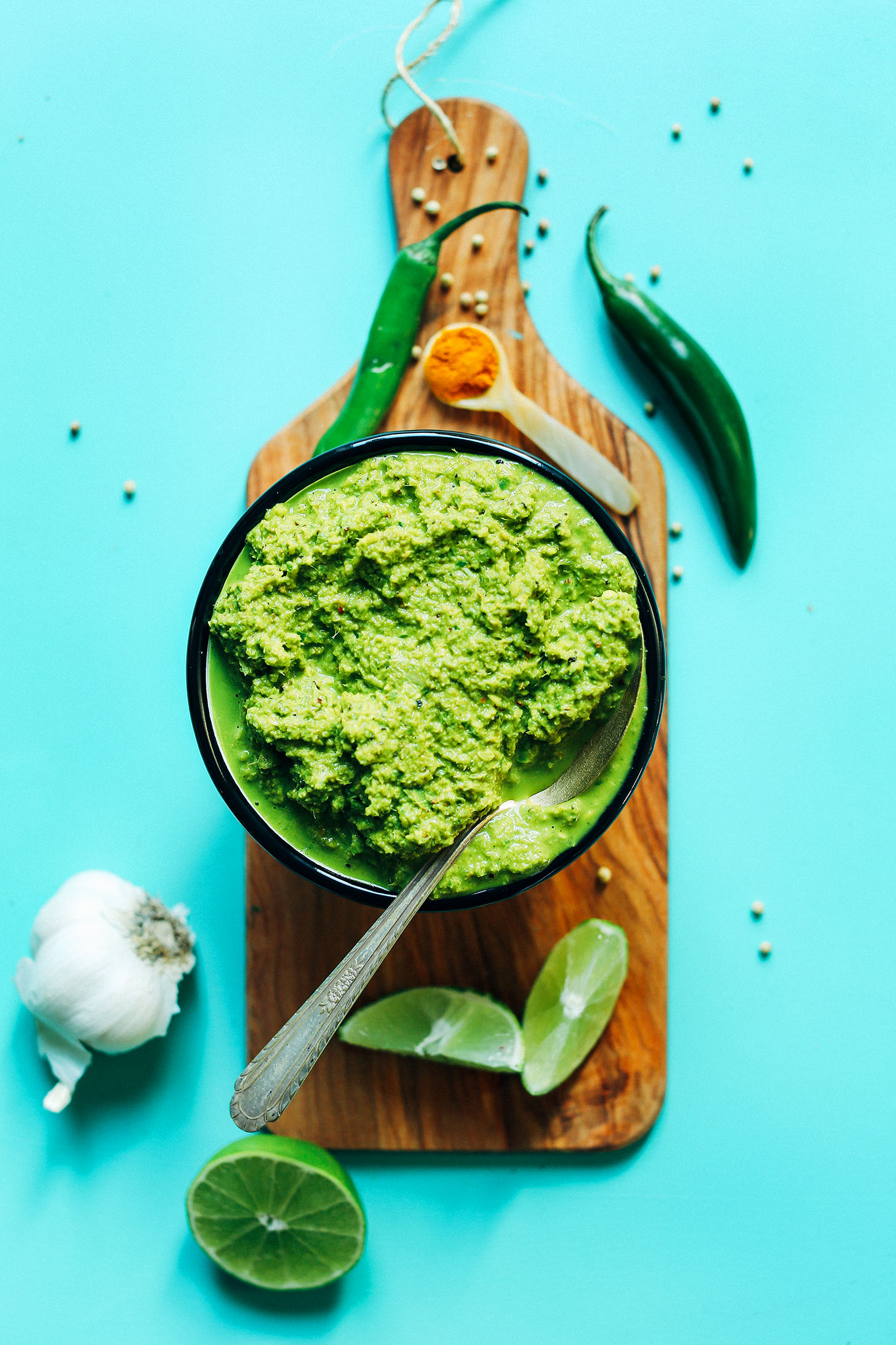 Wood board with a bowl of homemade Green Curry Paste and ingredients used to make it