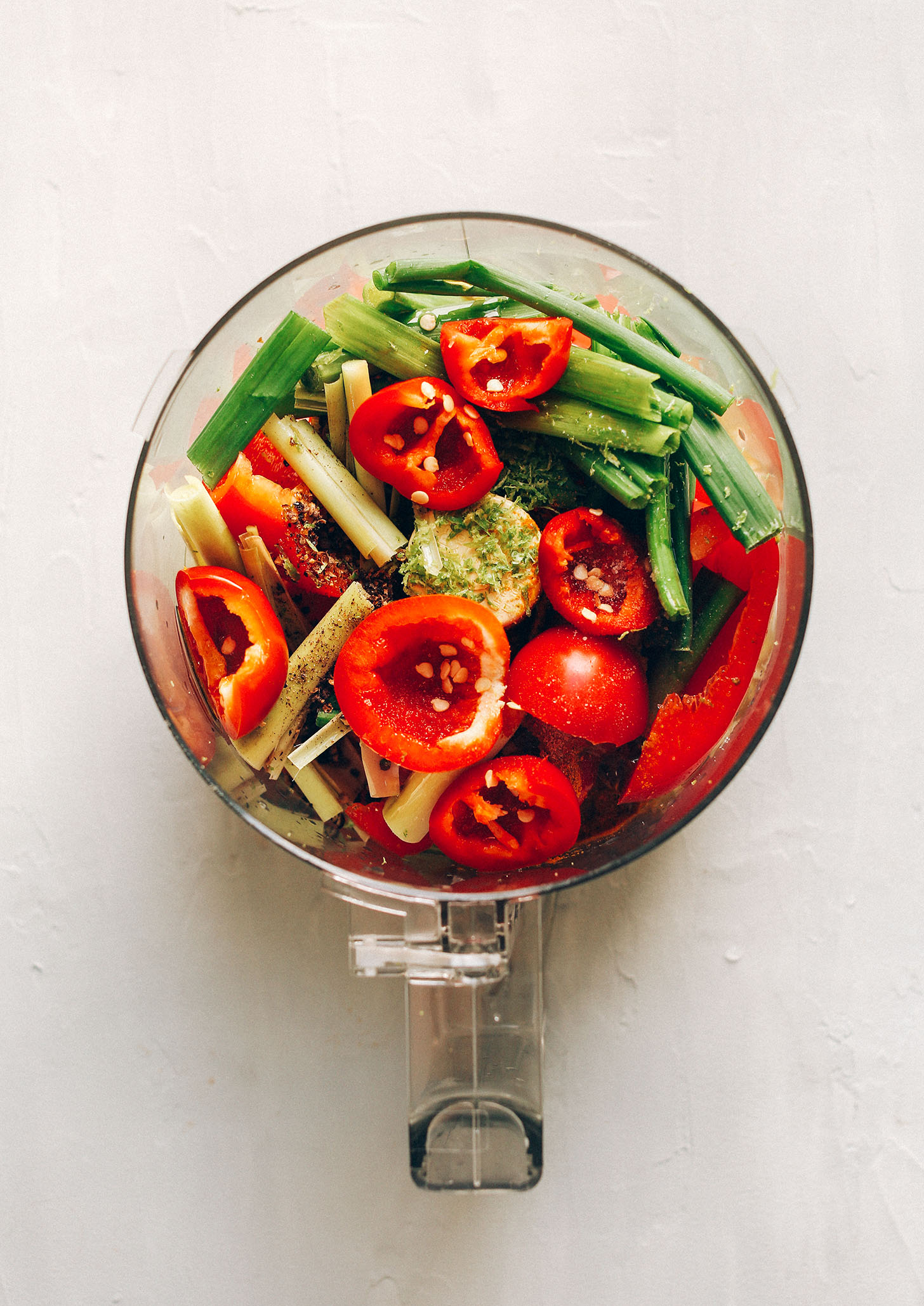 Food processor filled with peppers, green onion, lemongrass, and spices