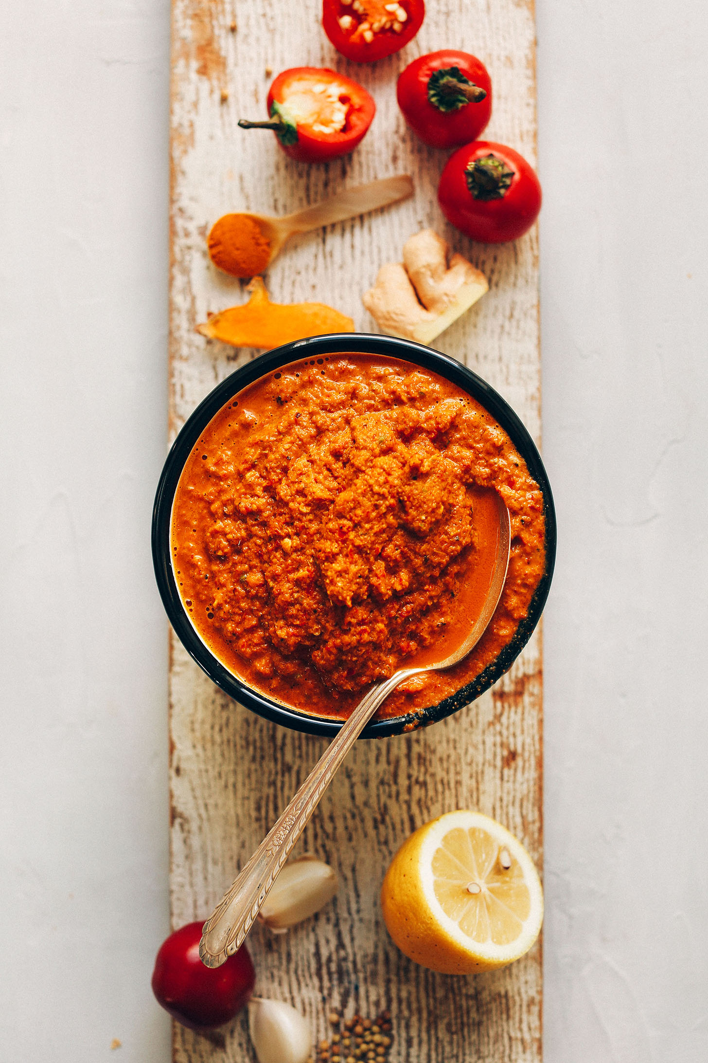 Wood plank with a bowl of Easy DIY Red Curry Paste and ingredients used to make it