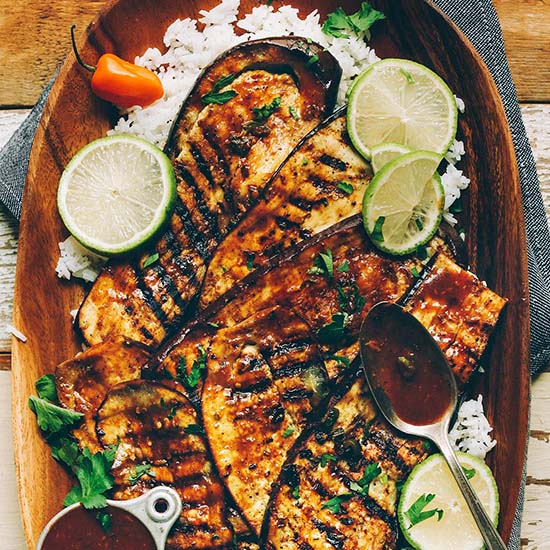 Wood platter filled with Vegan Jerk Eggplant slices over white rice