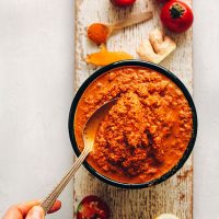 Using a spoon to scoop up homemade Red Curry Paste from a bowl