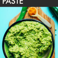 Bowl of easy vegan green curry paste with ingredients surrounding it