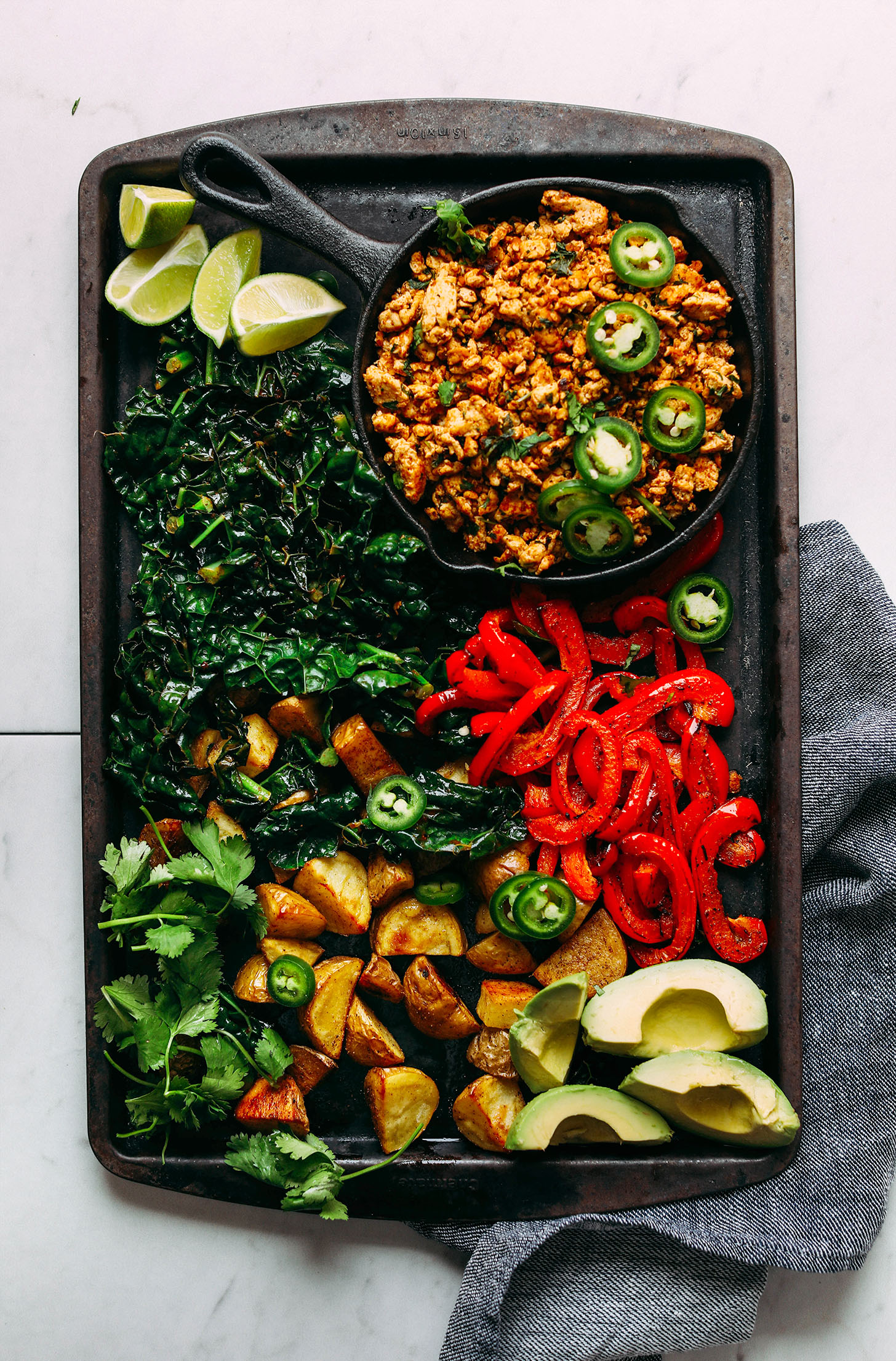 Scrambled tofu, roasted bell pepper, kale, potatoes, avocado, cilantro, and limes for Vegan Breakfast Burritos