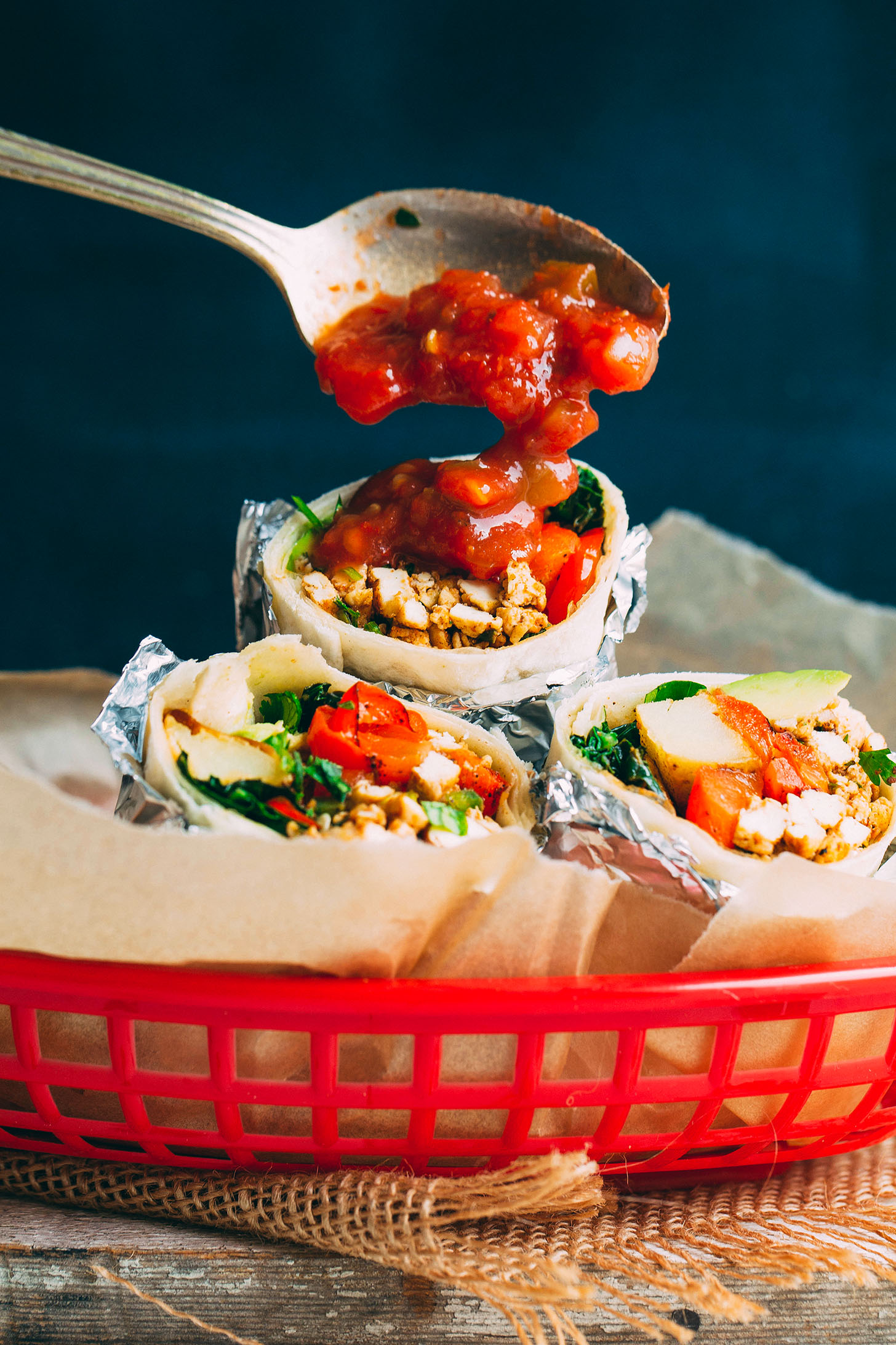 Using a spoon to pour salsa onto a healthy Vegan Breakfast Burrito