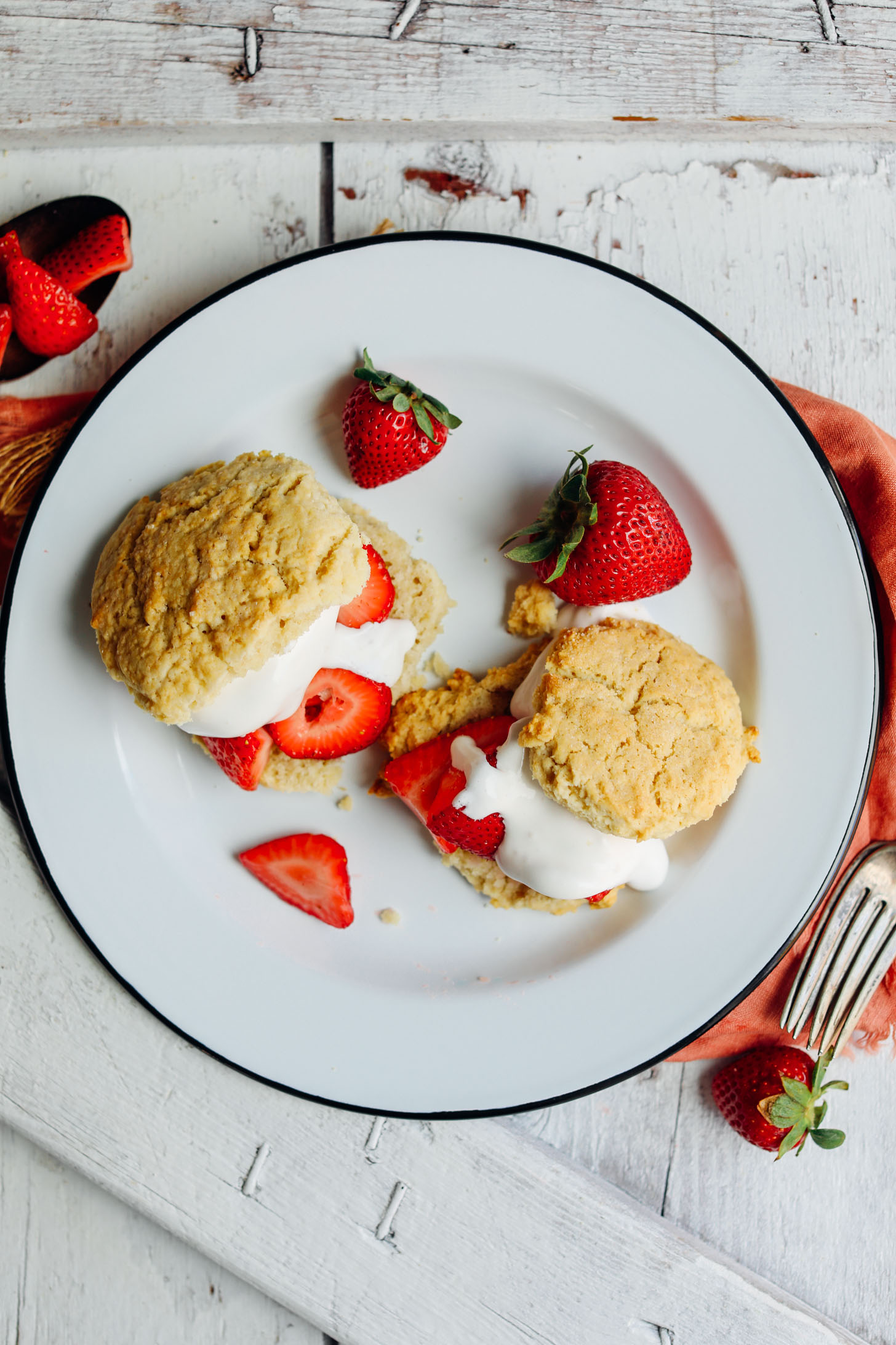 Top down photo showing perfectly browned vegan shortcake biscuits stuffed with fresh strawberries and coconut whipped cream