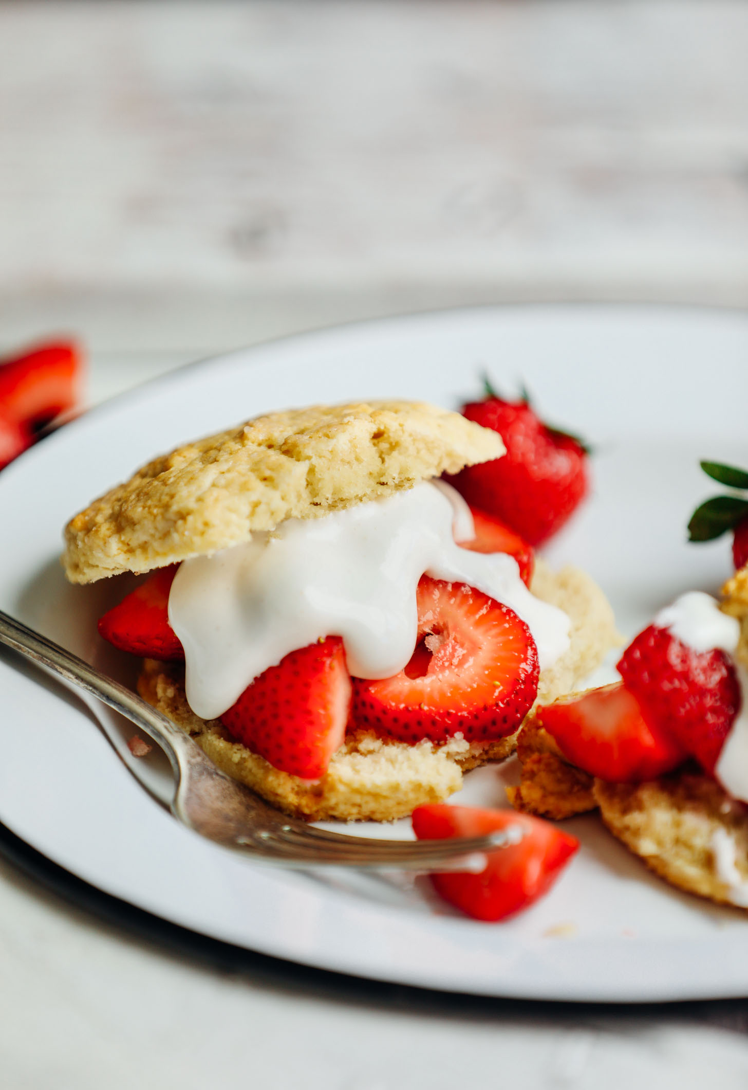 Plate with a vegan gluten-free shortcake biscuit with fresh strawberries and coconut whipped cream