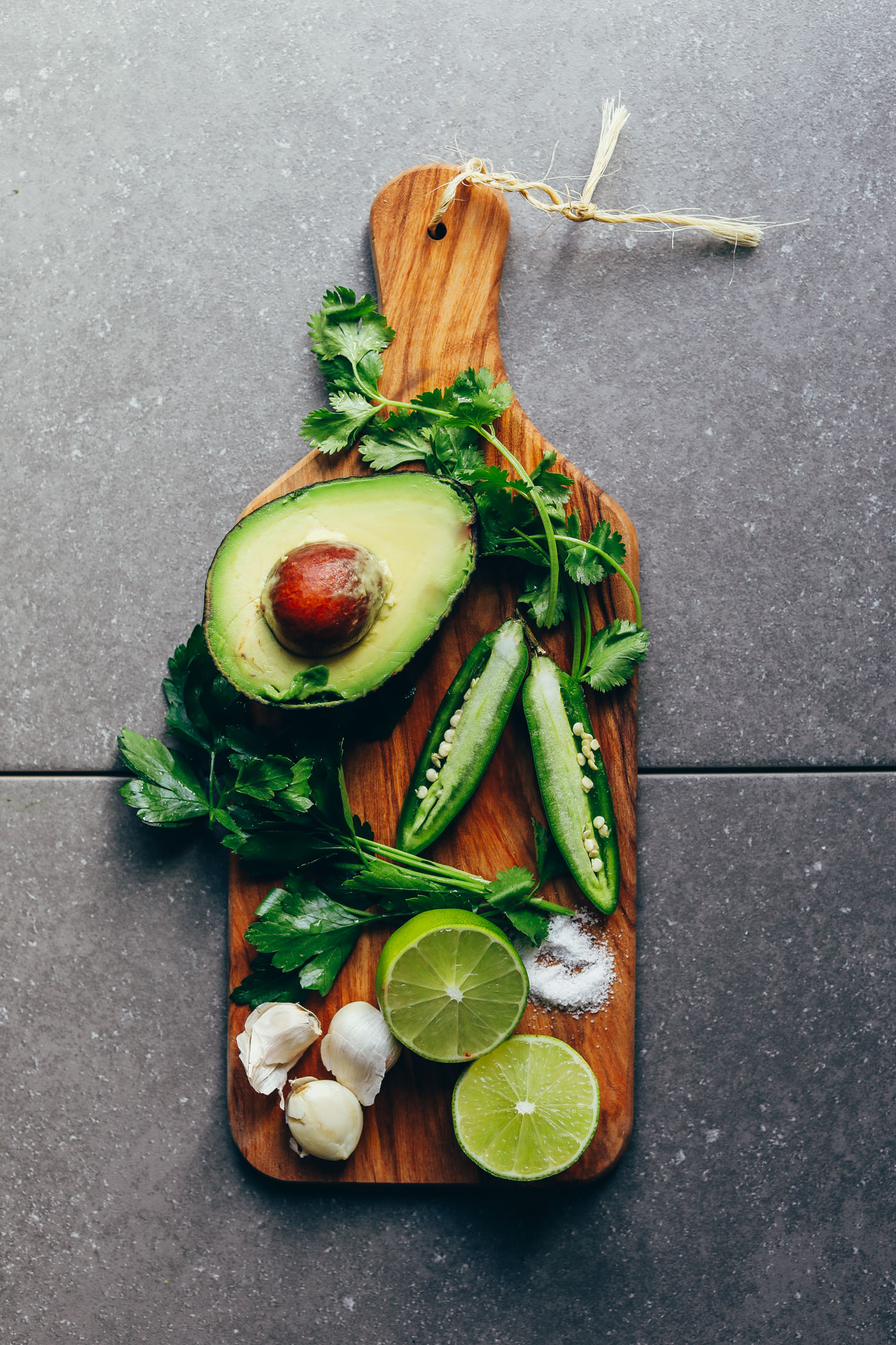 Avocado, jalapeno, cilantro, parsley, lime, salt, and garlic on a wood cutting board for making delicious Green Chimichurri
