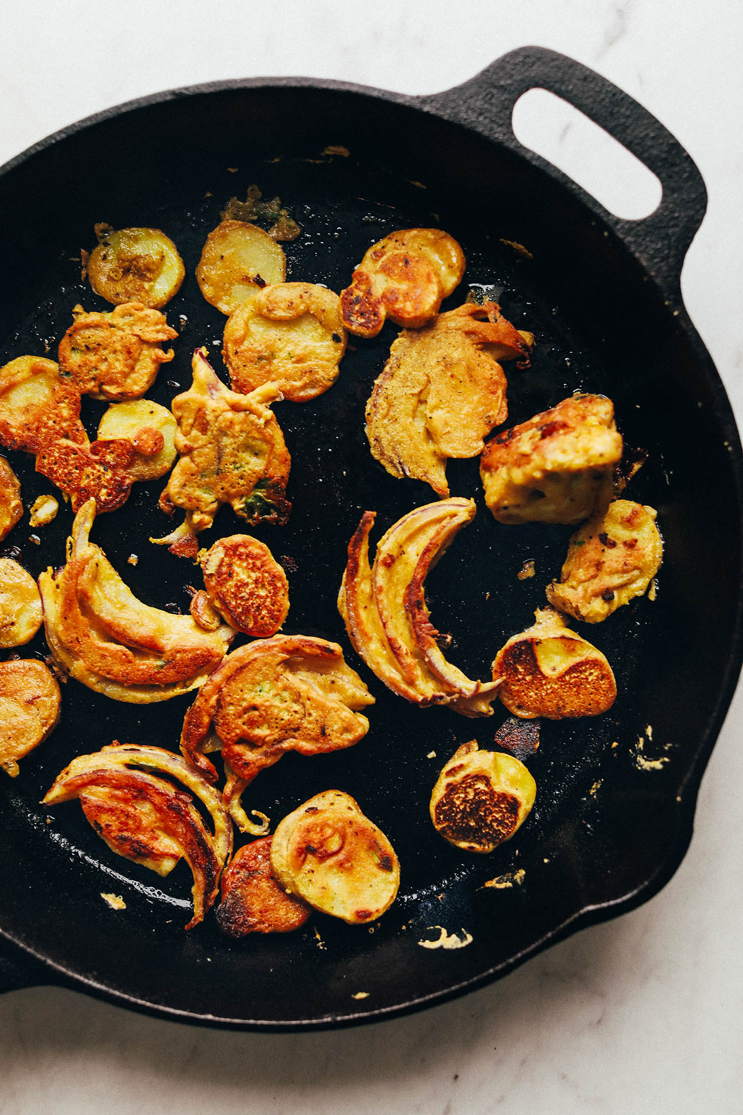 Pan frying Vegetable Pakoras in a cast-iron skillet