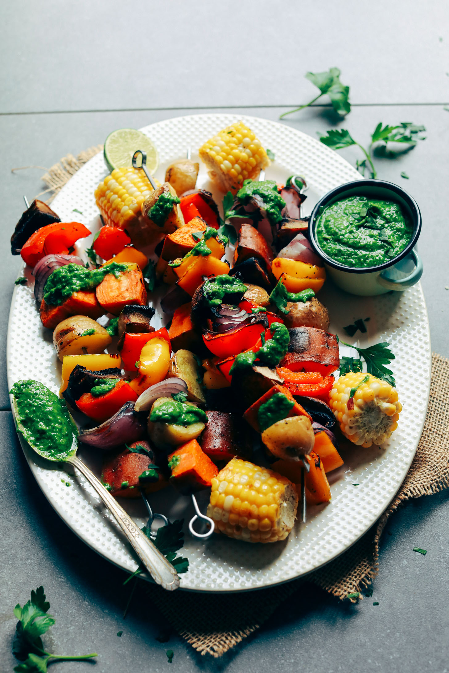 Ceramic platter filled with Grilled Veggie Skewers and drizzled with Chimichurri