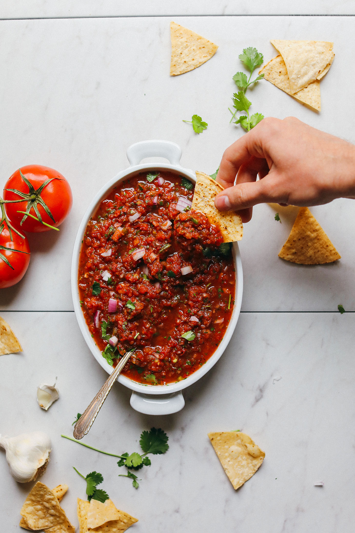 Dipping a tortilla chip into a bowl of our Perfect Red Salsa recipe