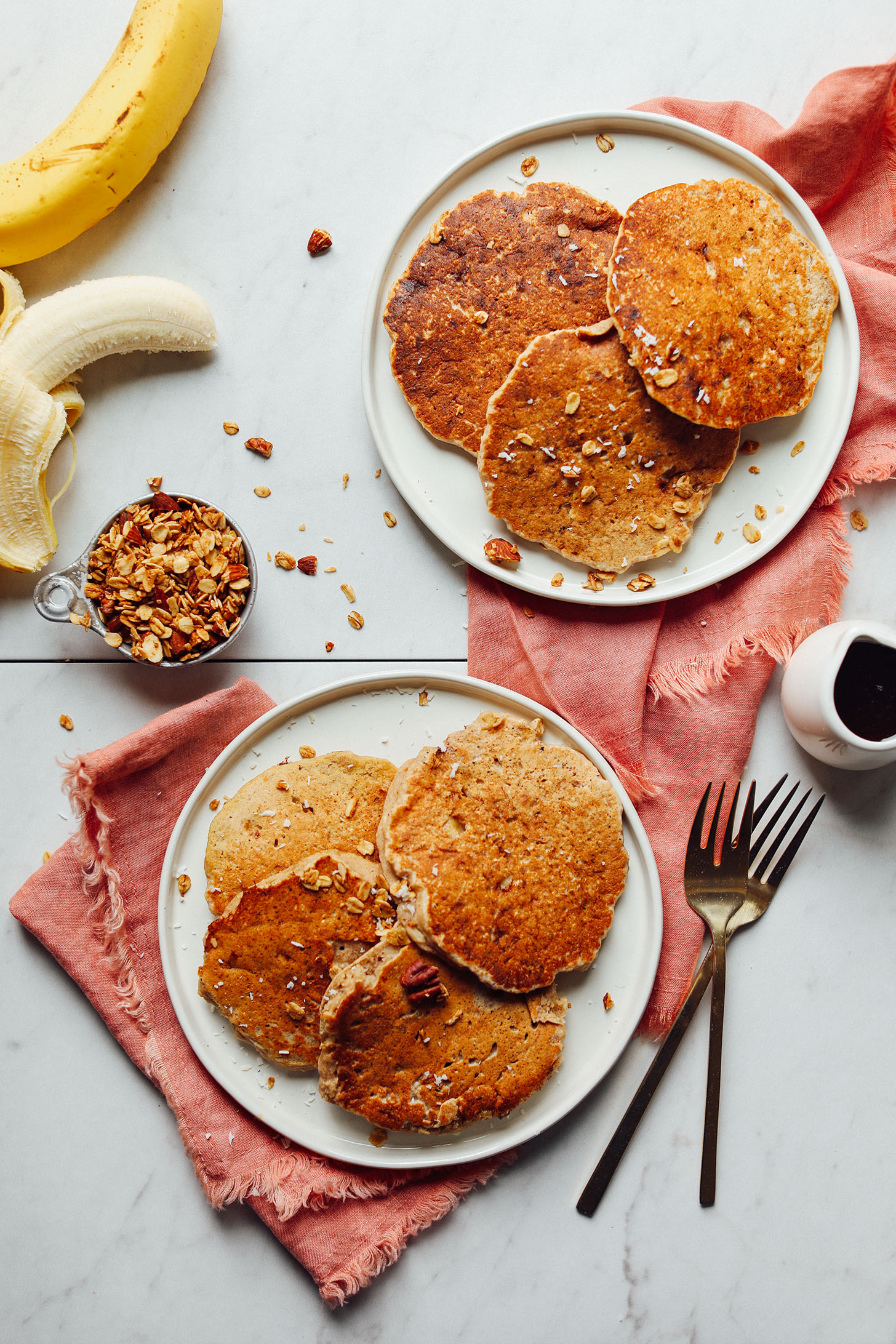 Two plates with gluten-free vegan Banana Pancakes sprinkled with granola