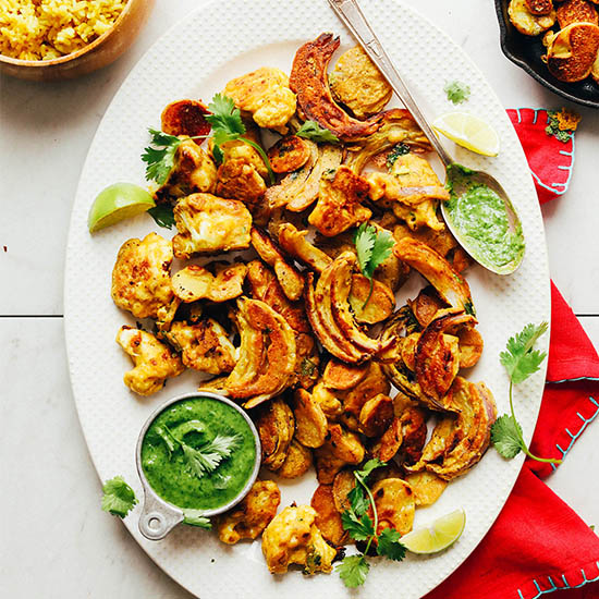 Platter of our delicious Vegetable Pakoras alongside a measuring cup filled with chutney