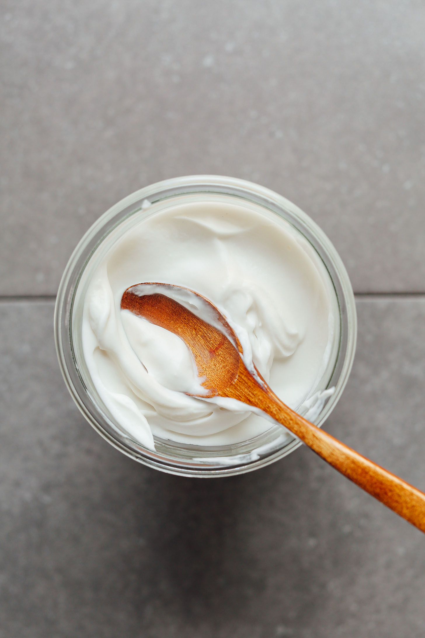 Using a wooden spoon to stir homemade Coconut Yogurt