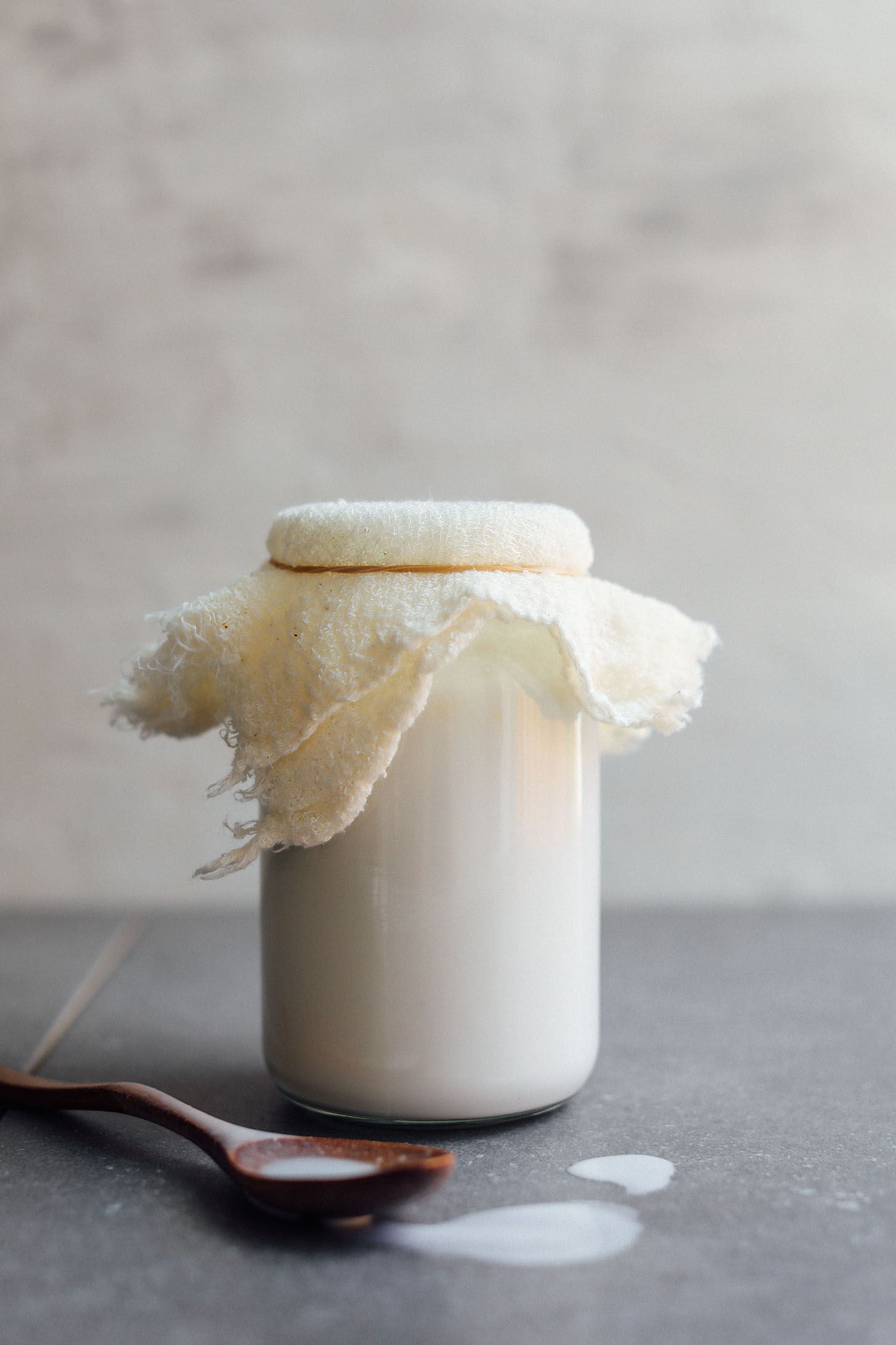 Jar of coconut yogurt covered with a cheesecloth and secured with a rubberband