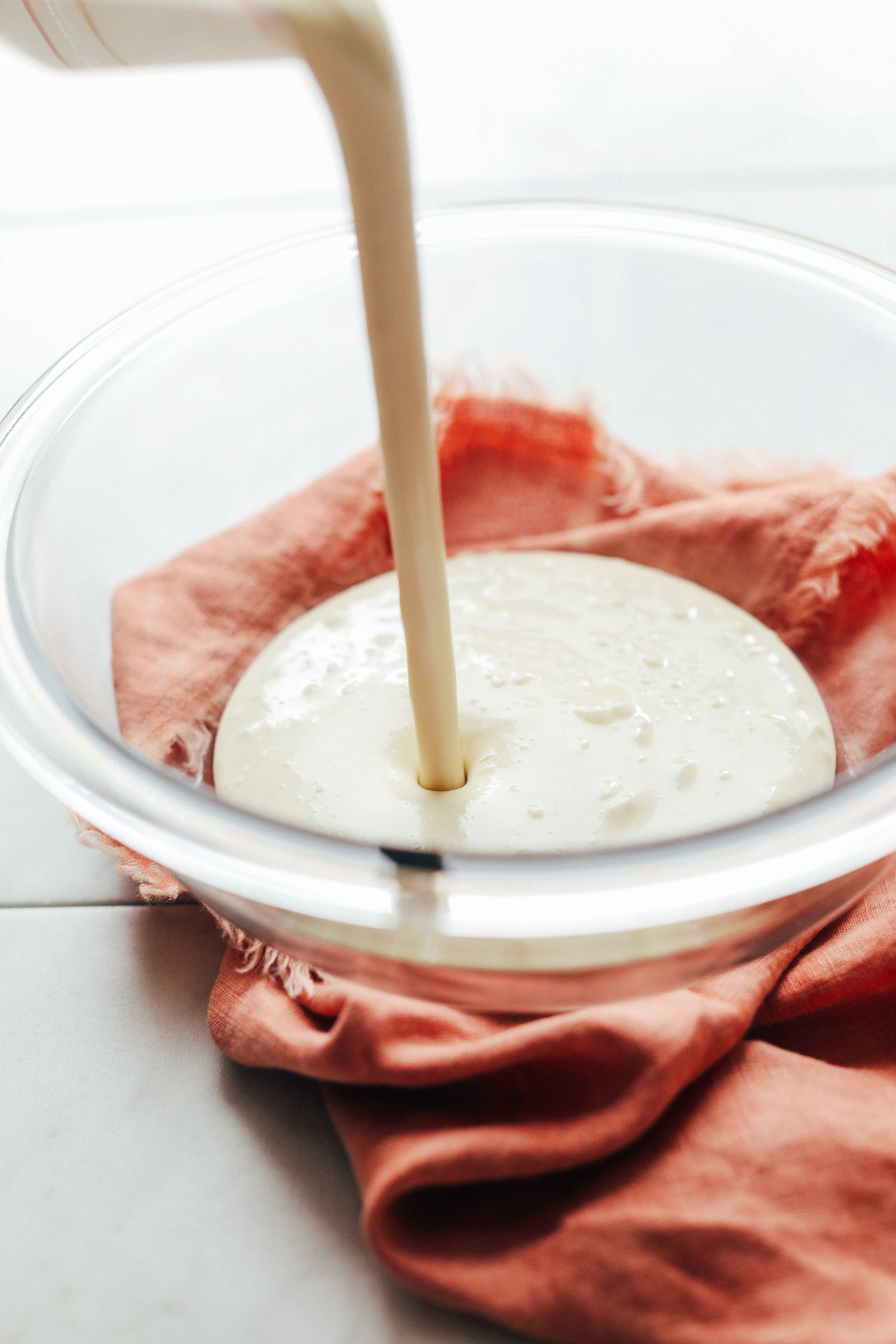 Pouring blended frosting ingredients into a mixing bowl