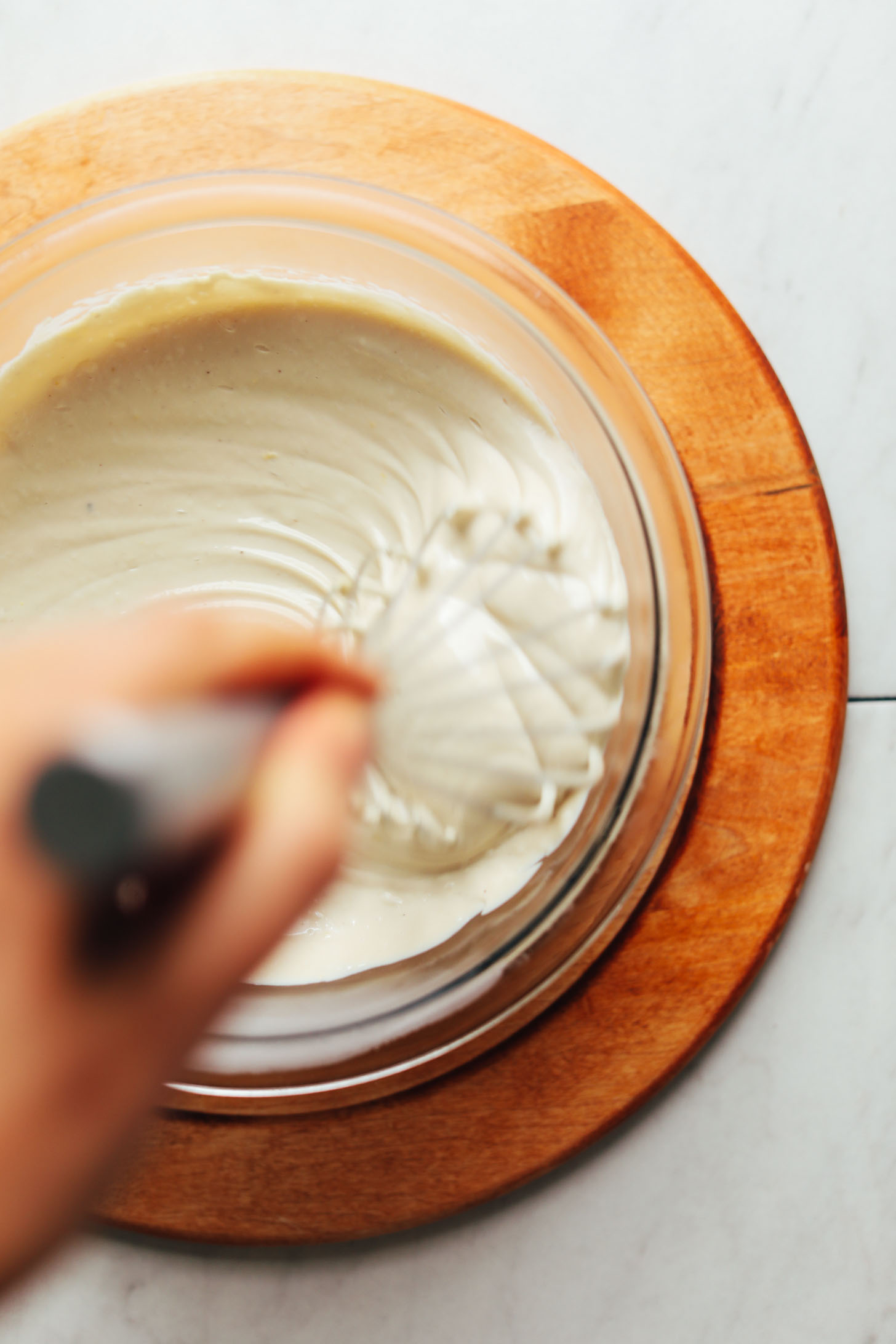 Whisking vegan Cashew Buttercream Frosting in a mixing bowl